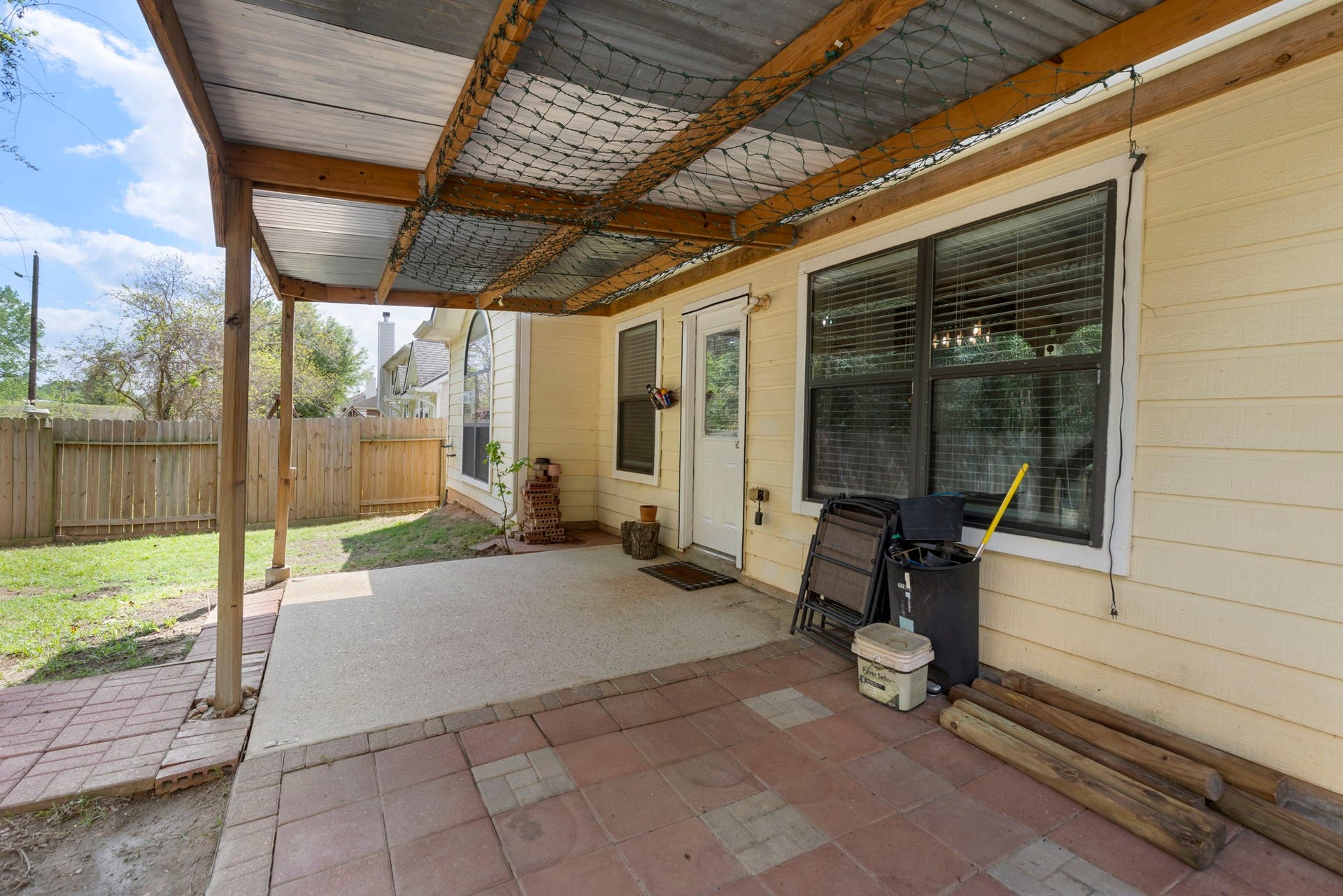 8022 N Tarrytown Crossing Drive, Conroe, TX 77304 Charming covered patio area perfect for outdoor relaxation, featuring a sturdy wooden cover and access to a fenced backyard.