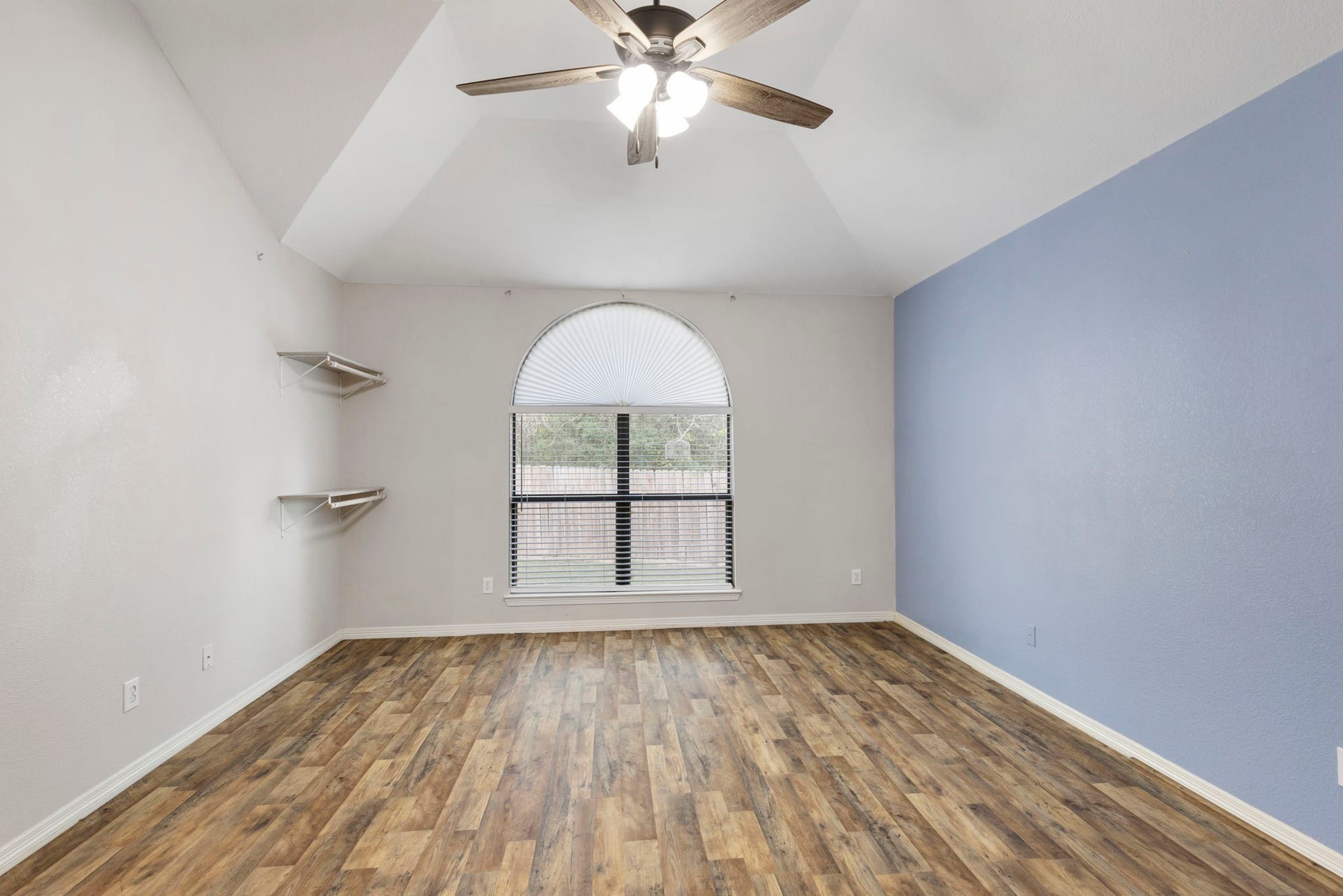 8022 N Tarrytown Crossing Drive, Conroe, TX 77304 Experience serene comfort in this primary bedroom, featuring vaulted ceilings, elegant laminateflooring, and a large arched window that bathes the space in natural light.