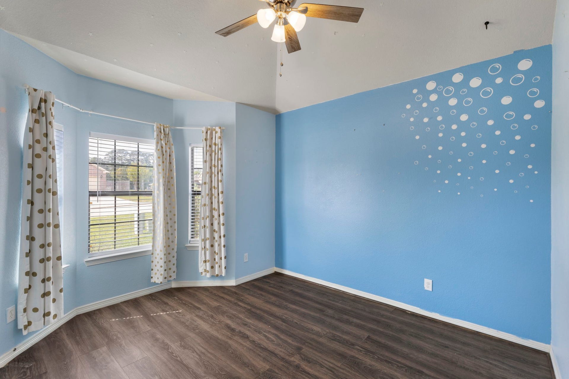 8022 N Tarrytown Crossing Drive, Conroe, TX 77304 Bright and inviting room with large bay windows, charming polka dot curtains, and a whimsical bubble accent wall.