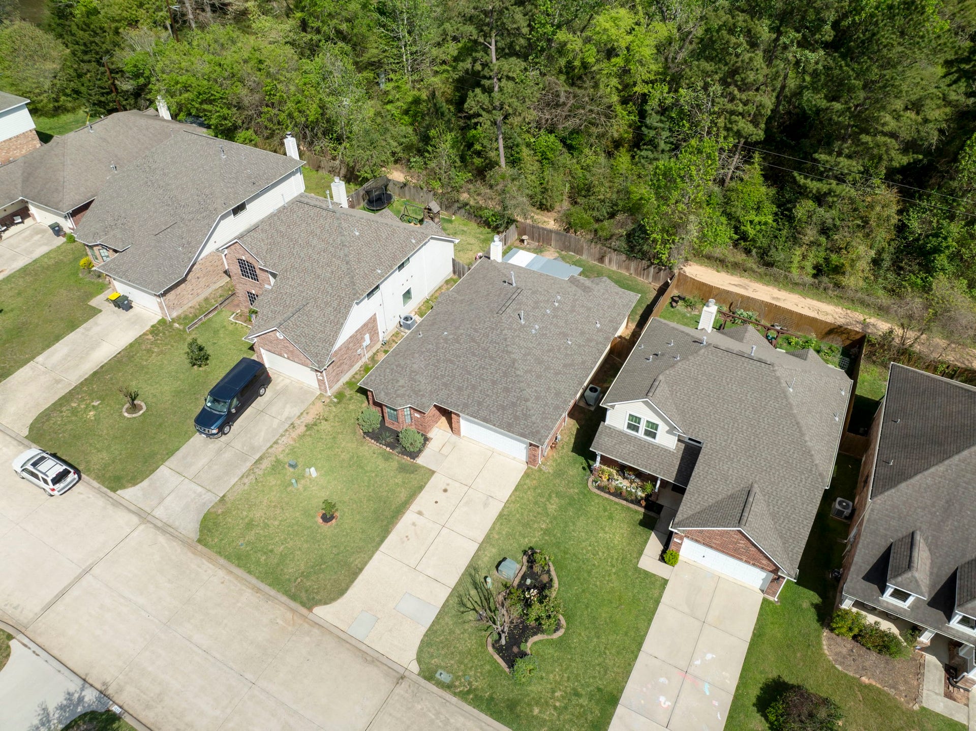 8022 N Tarrytown Crossing Drive, Conroe, TX 77304 Charming suburban homes with spacious driveways and well-maintained lawns, nestled alongside a serene wooded area for added privacy and natural beauty.
