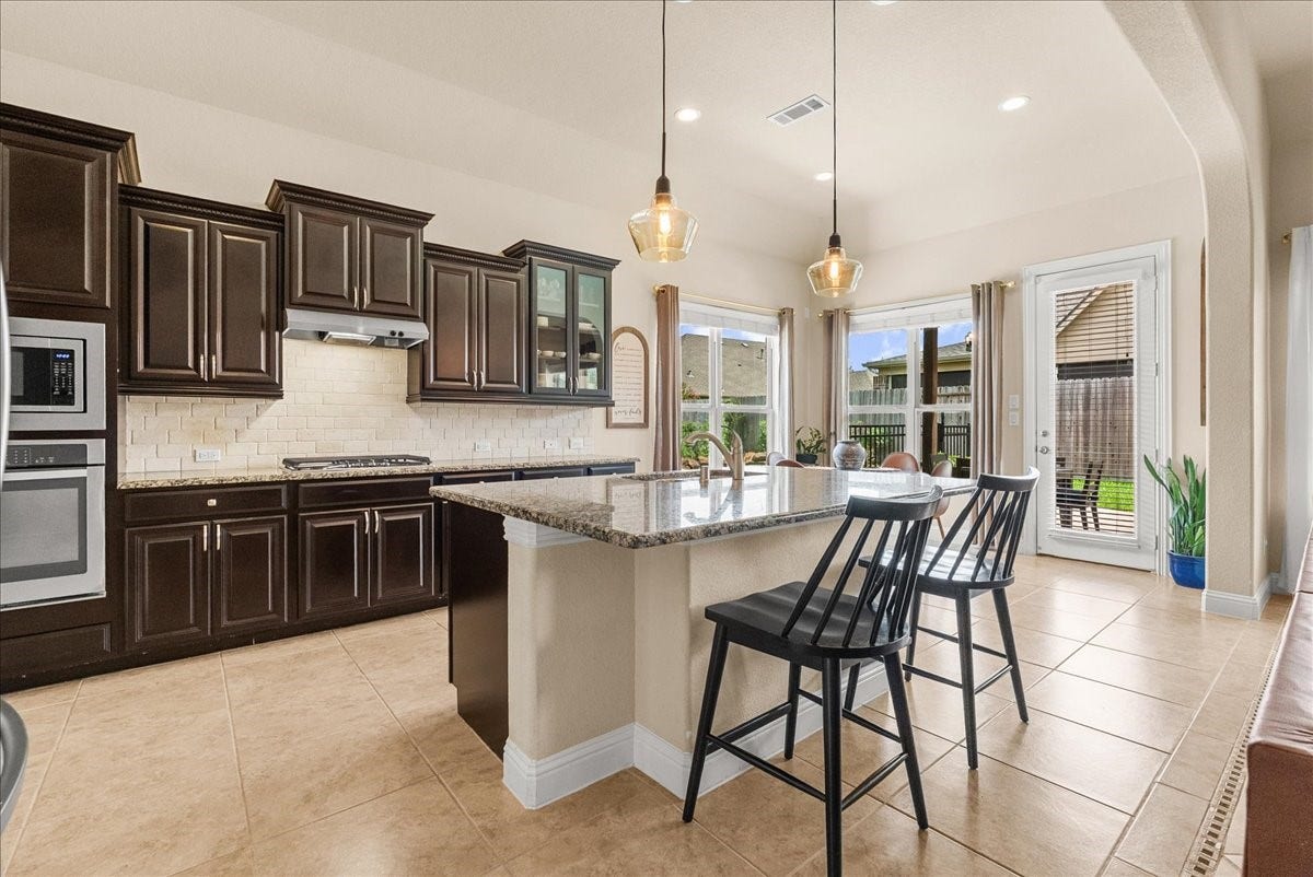 1413 Coffee Mill Court, League City, TX 77573 The chef-inspired kitchen with 42" cabinetry, crown molding, granite countertops, designer backsplash, stainless steel appliances, walk-in pantry, and butlers pantry.