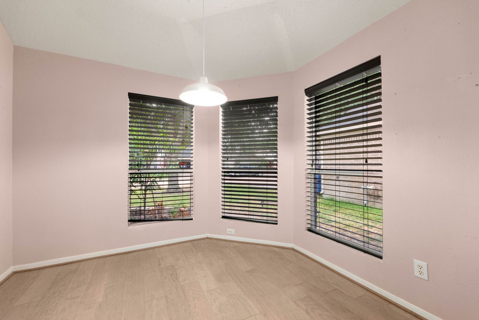 Breakfast area features three windows that bring in natural light, light wood-look flooring, and a pendant light for casual dining.