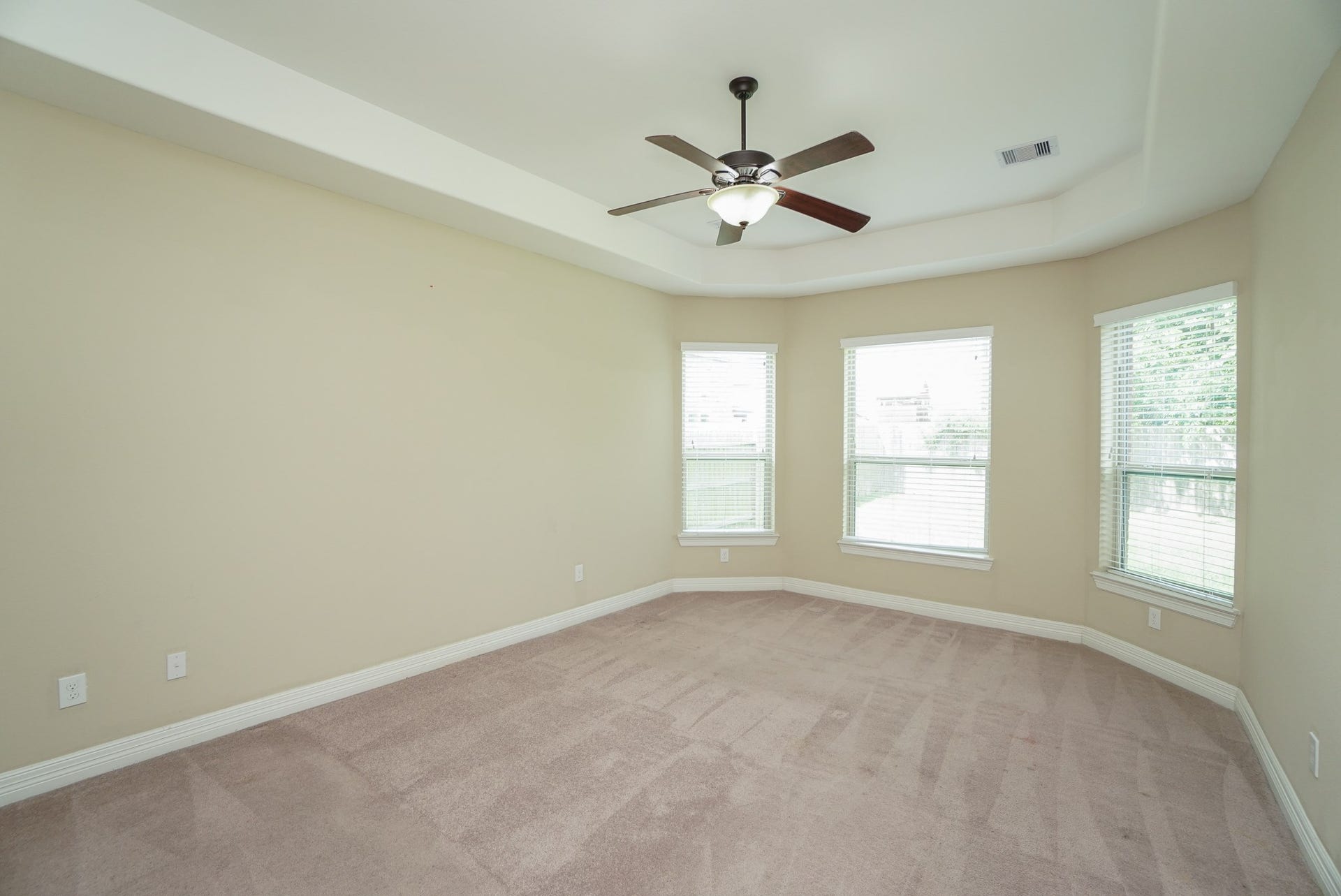 3434 Norwich Gardens Lane, Fulshear, TX 77441 The spacious primary suite offers plenty of natural light, tray ceiling, and a view of the backyard.