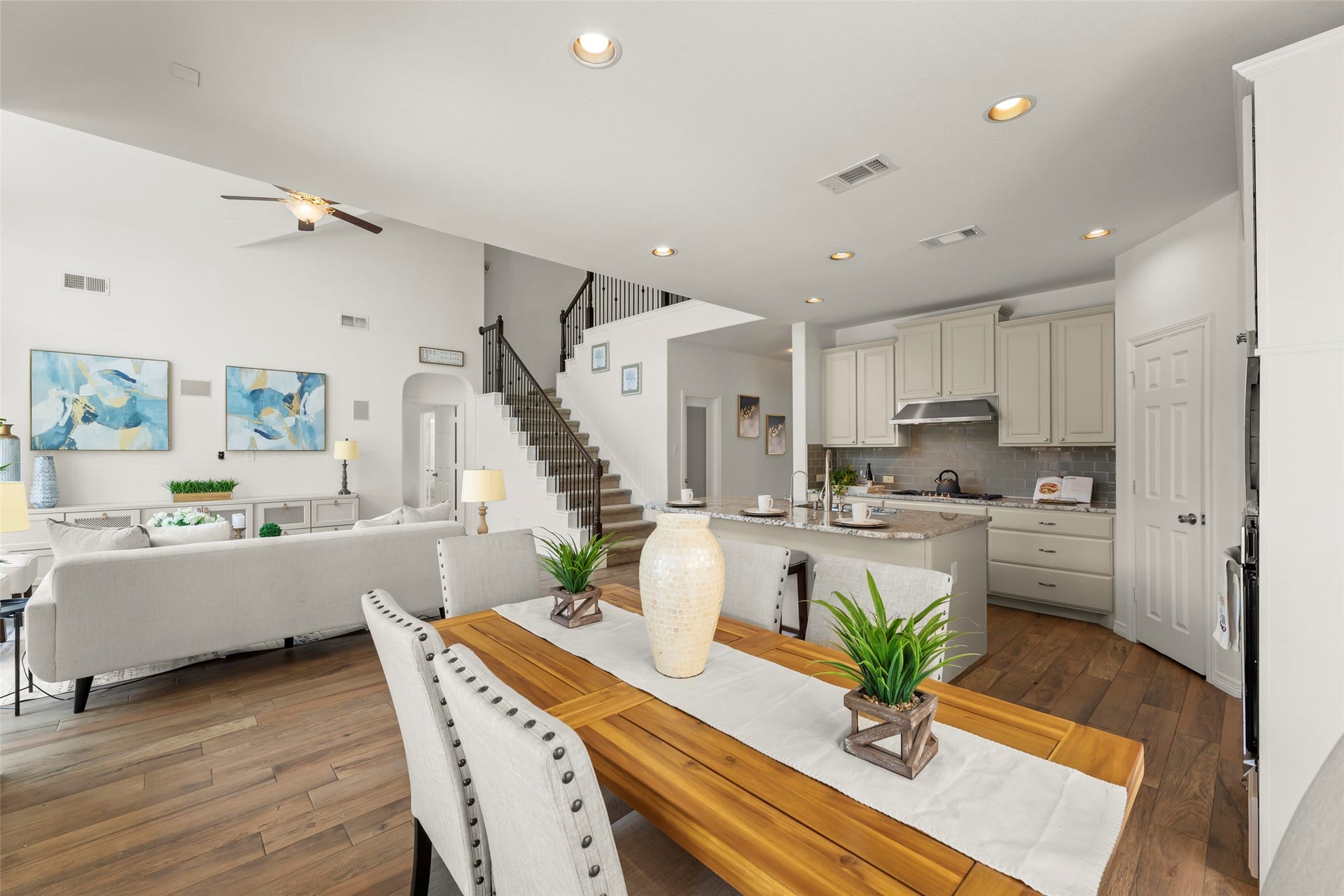 Seamless flow from the modern kitchen with sleek cabinetry to the inviting living room. A grand staircase leads to the upper level, enhancing the home's airy ambiance.