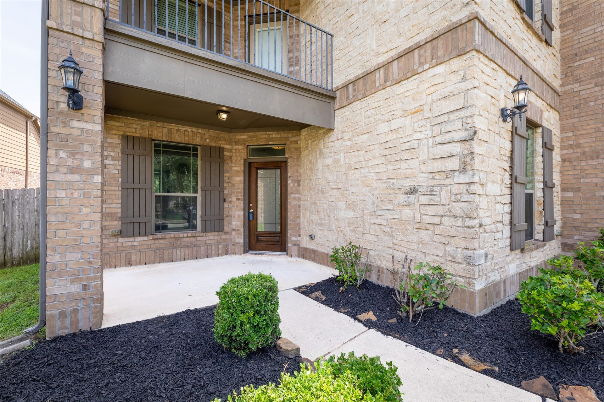 Covered porch, elegant stone and brick exterior, and inviting landscaping.