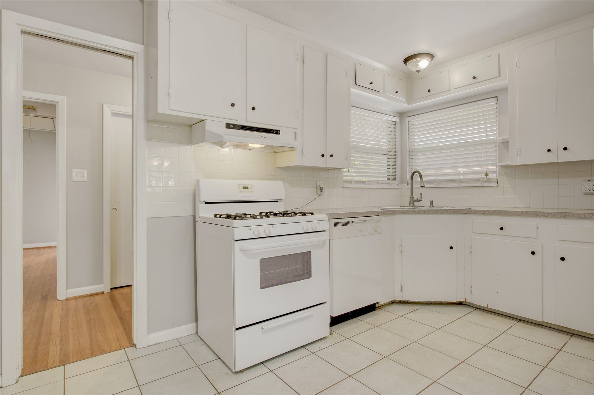 4314 Benning Drive, Houston, TX 77035 White tiled kitchen with freestanding gas range, corner sink, opening to both the flex room and foyer.