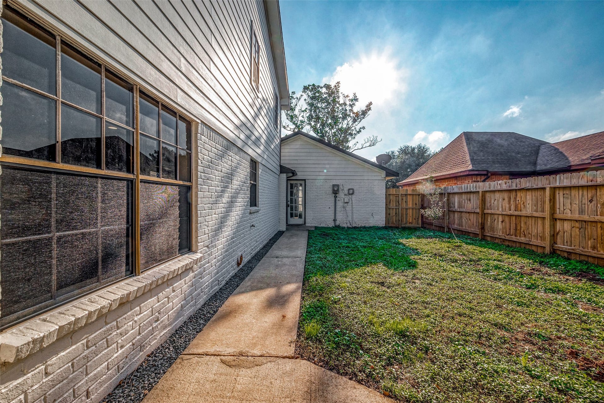 3102 Glenn Lakes Lane, Missouri City, TX 77459 A cozy backyard with a concrete path, grassy area, and a wooden fence.