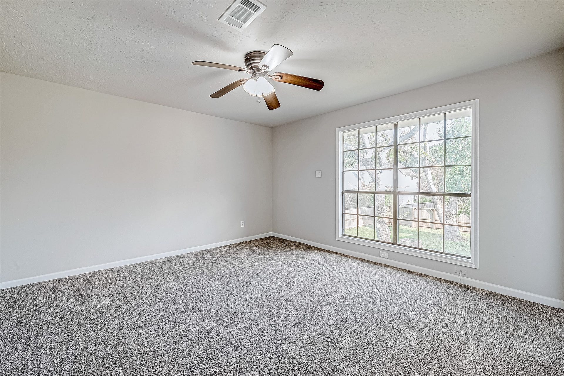 3102 Glenn Lakes Lane, Missouri City, TX 77459 Bright and inviting bedroom with a large window overlooking the backyard, cozy carpet, and a ceiling fan with lights.
