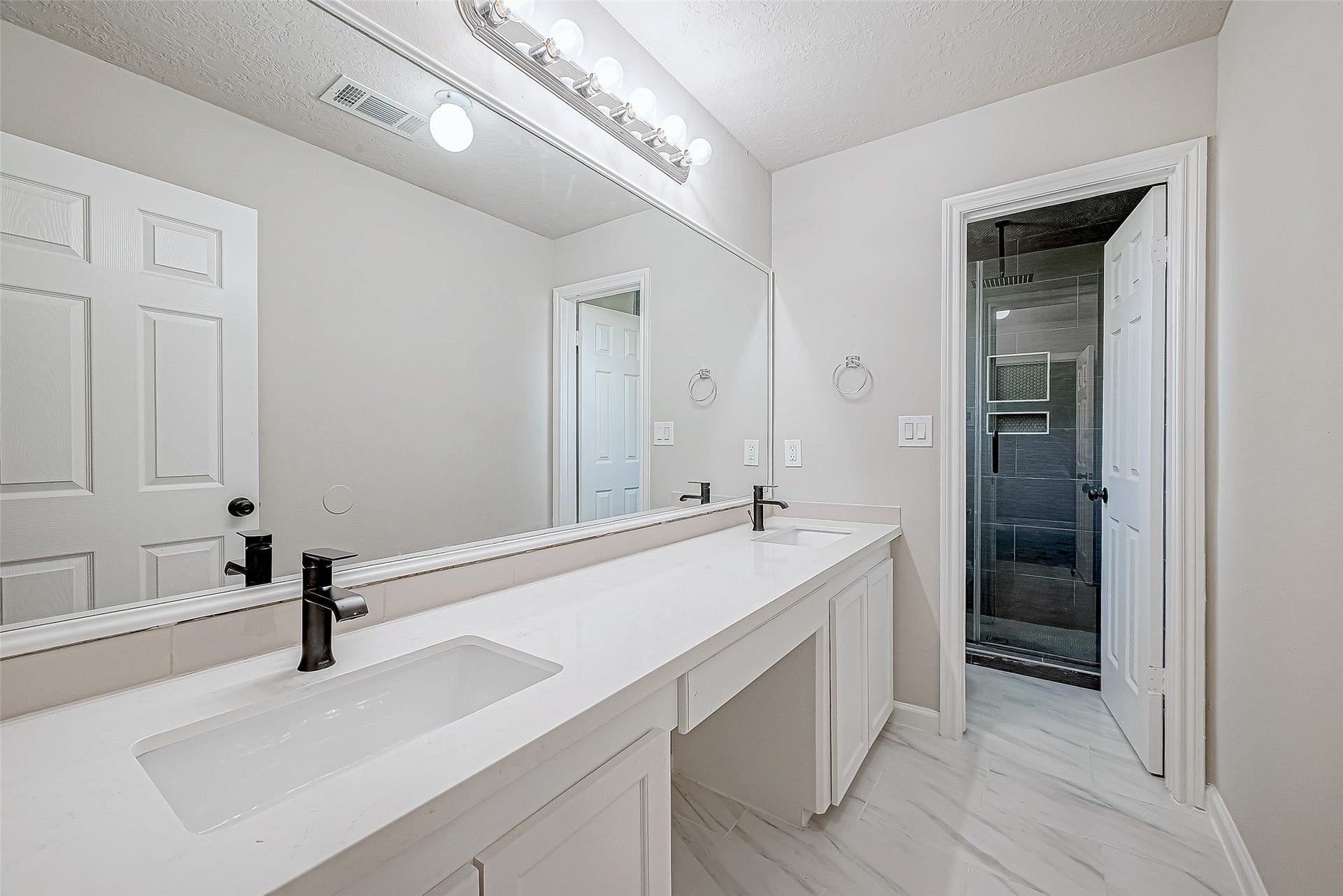 3102 Glenn Lakes Lane, Missouri City, TX 77459 This bathroom features a double vanity with sleek black faucets, large mirror, and a stylish walk-in shower with dark tiling, creating a clean and contemporary look.