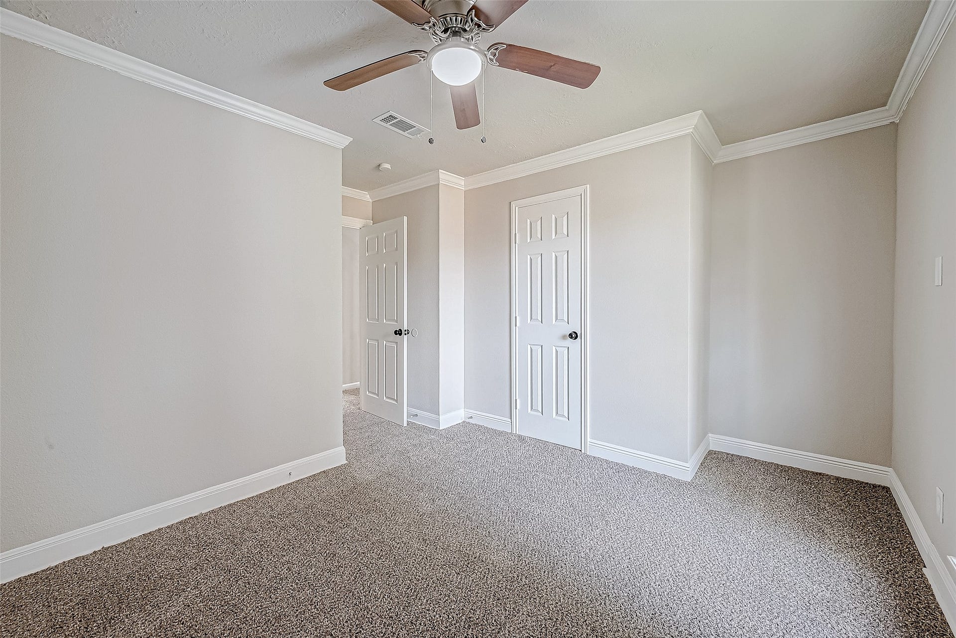 3102 Glenn Lakes Lane, Missouri City, TX 77459 Bright and airy room with neutral tones, featuring carpet flooring, a ceiling fan, two doors, and elegant crown molding.