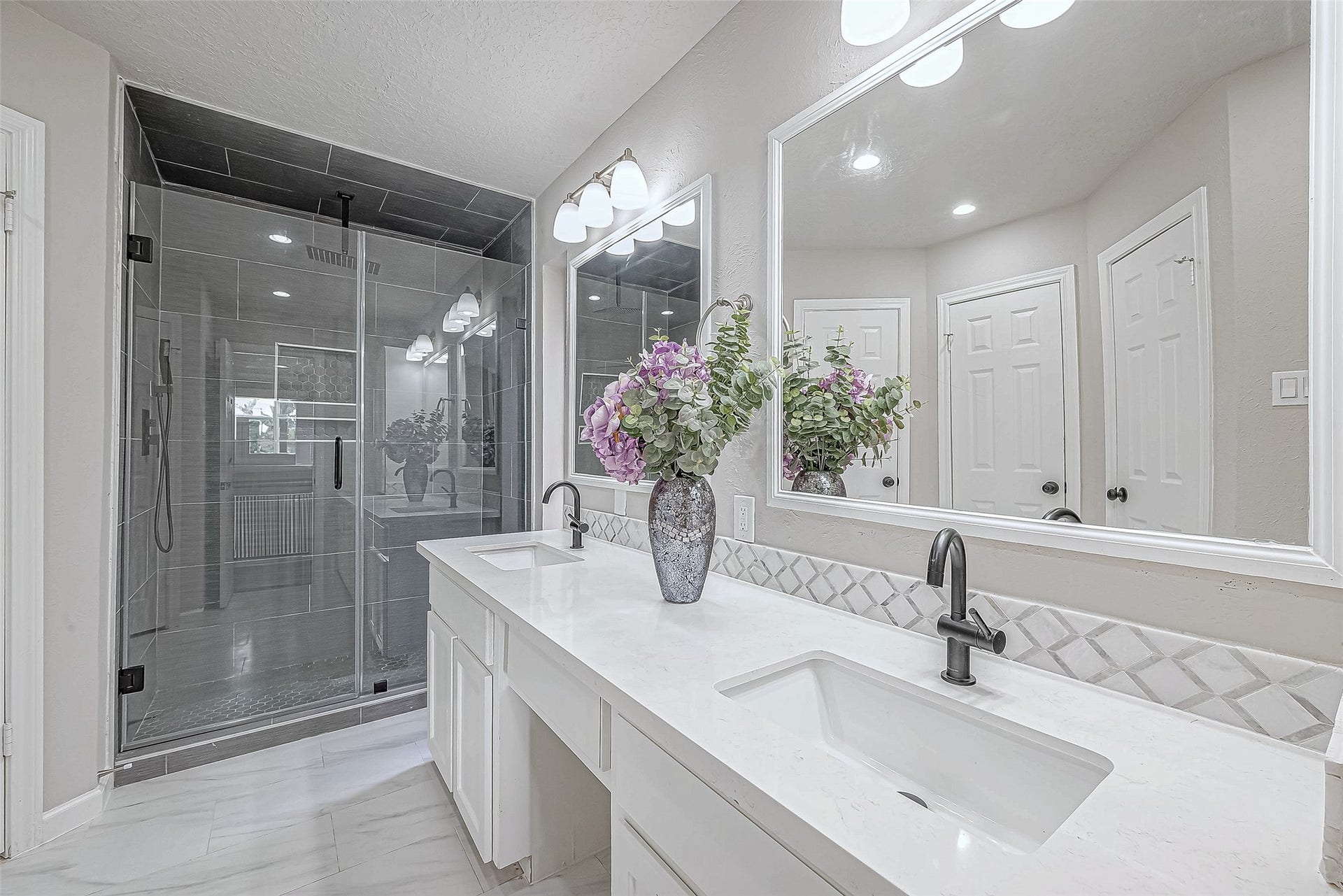3102 Glenn Lakes Lane, Missouri City, TX 77459 The primary bathroom with a spacious glass shower, dual sinks, sleek black fixtures, and large mirrors.