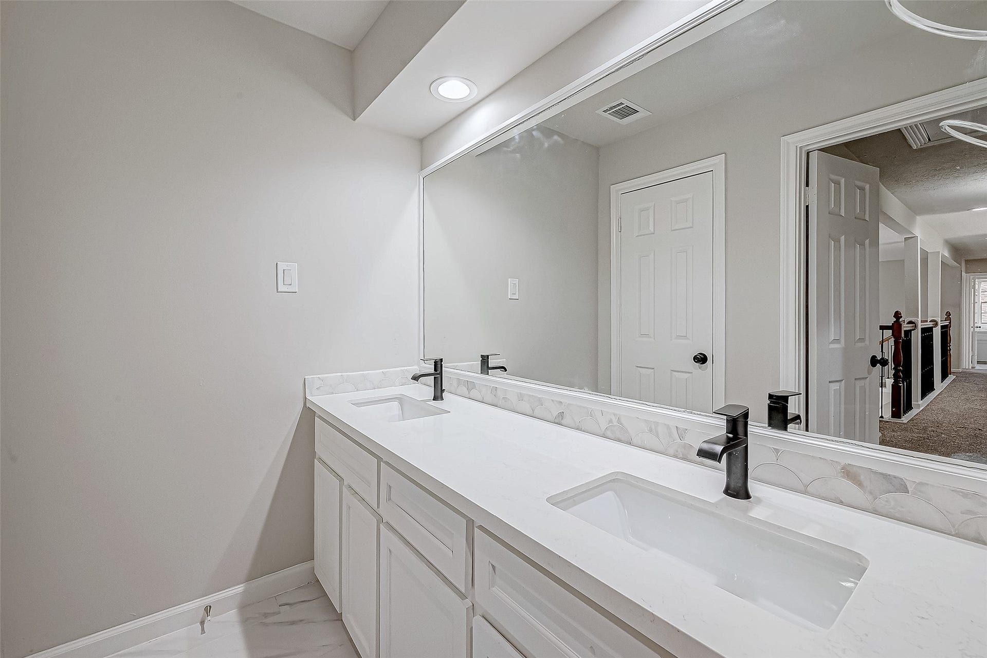 3102 Glenn Lakes Lane, Missouri City, TX 77459 A modern bathroom with a double vanity featuring sleek black faucets and a large mirror.