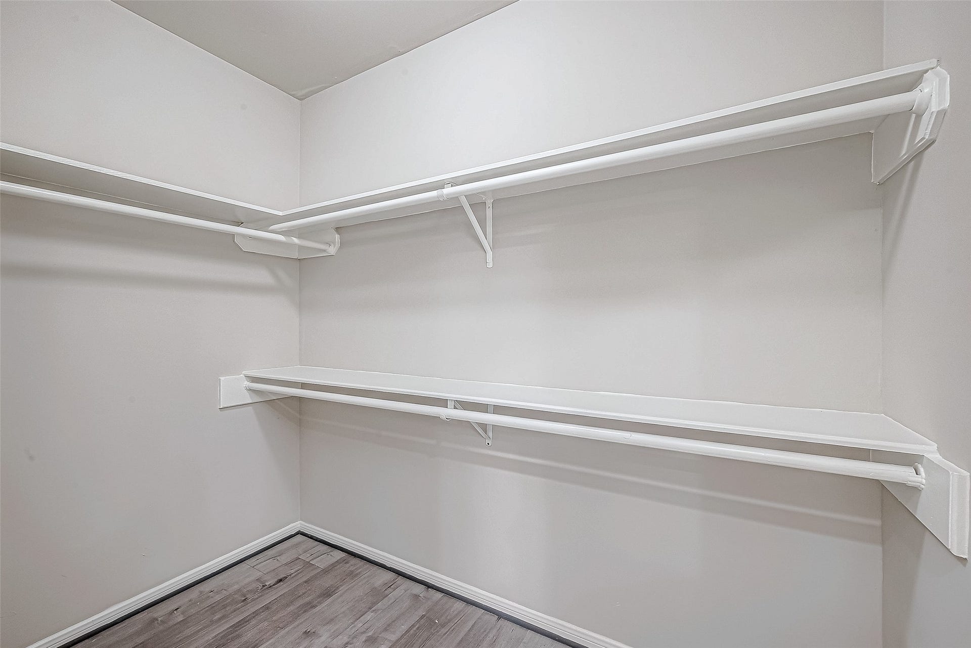 3102 Glenn Lakes Lane, Missouri City, TX 77459 Walk-in closet features sleek wood flooring, dual-level white shelving, and ample hanging rods for optimal organization.