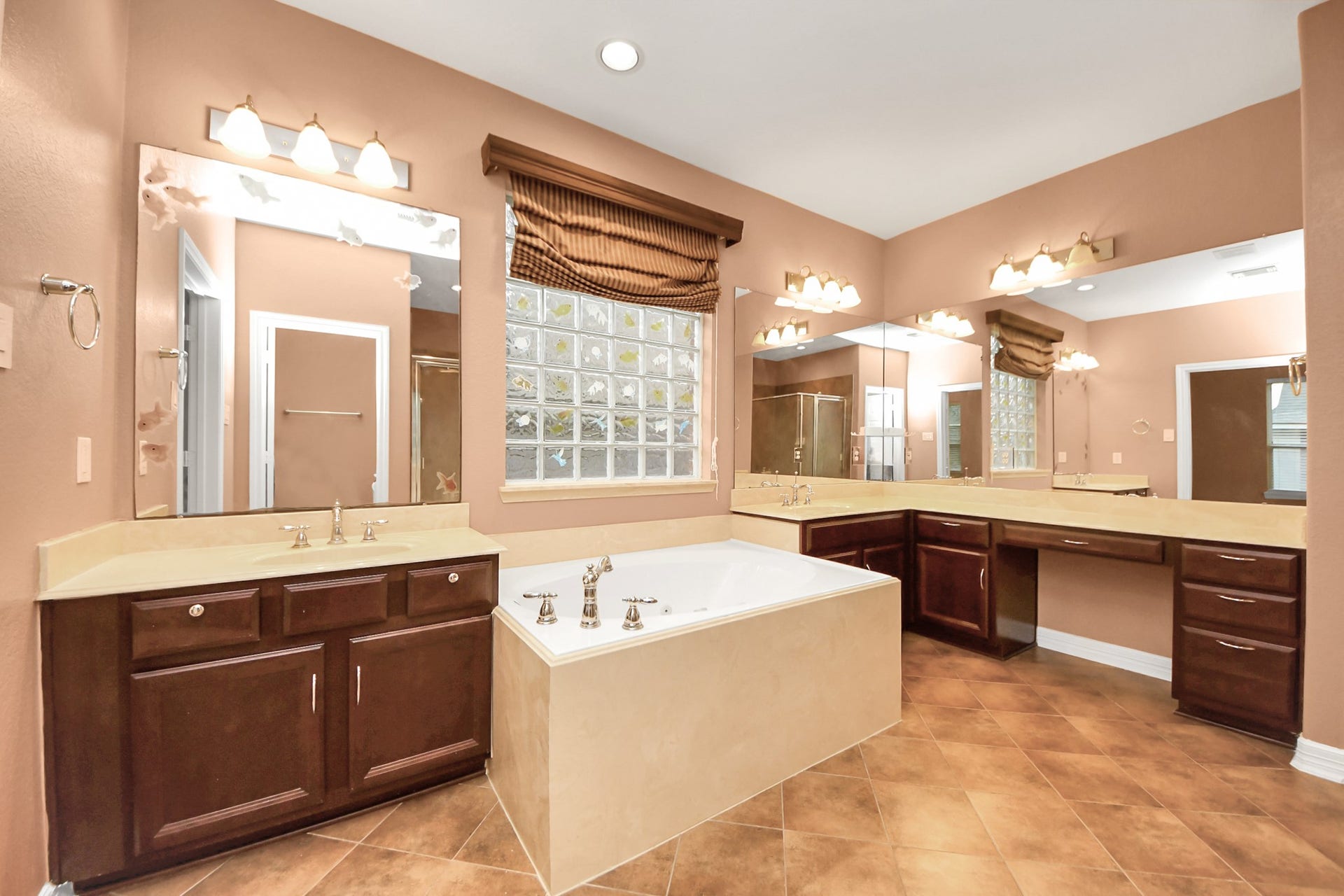 3003 Birch Landing Court, Pearland, TX 77584 The primary bath feels rich and luxurious with warm lighting, dual vanities, expansive counters, and a soaking tub beneath a glass block window.