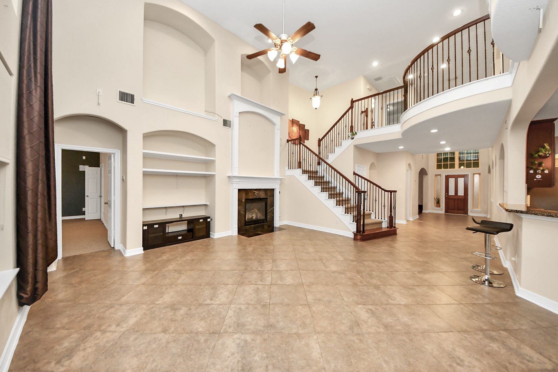 3003 Birch Landing Court, Pearland, TX 77584 The living area rises dramatically with its high ceilings, wall niches, and sightlines to the upper level, warmed by a striking fireplace.