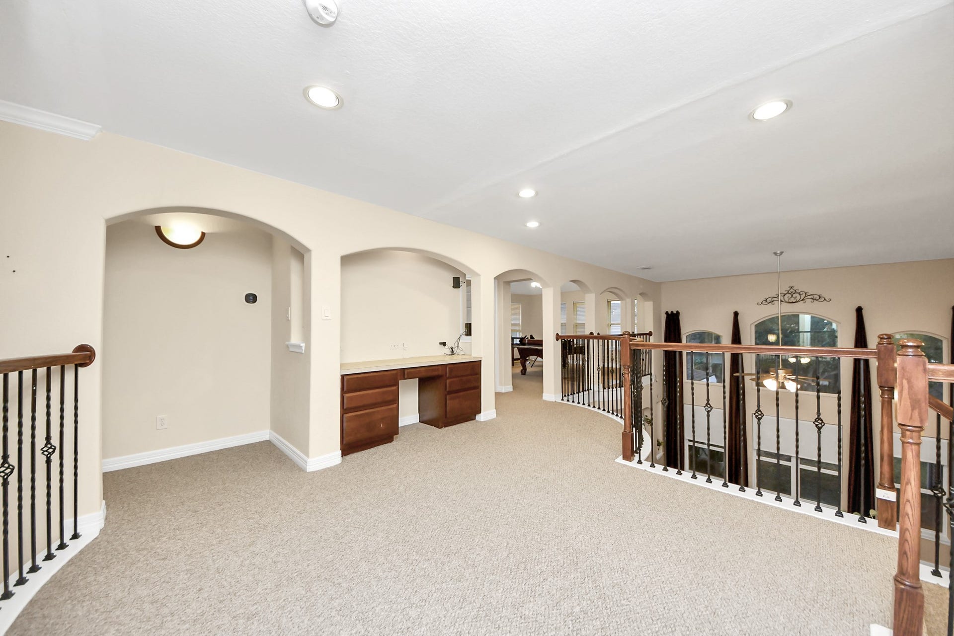 3003 Birch Landing Court, Pearland, TX 77584 The upper landing, wrapped in carpet, overlooks the main level and includes an integrated workstation beneath elegant wall arches.