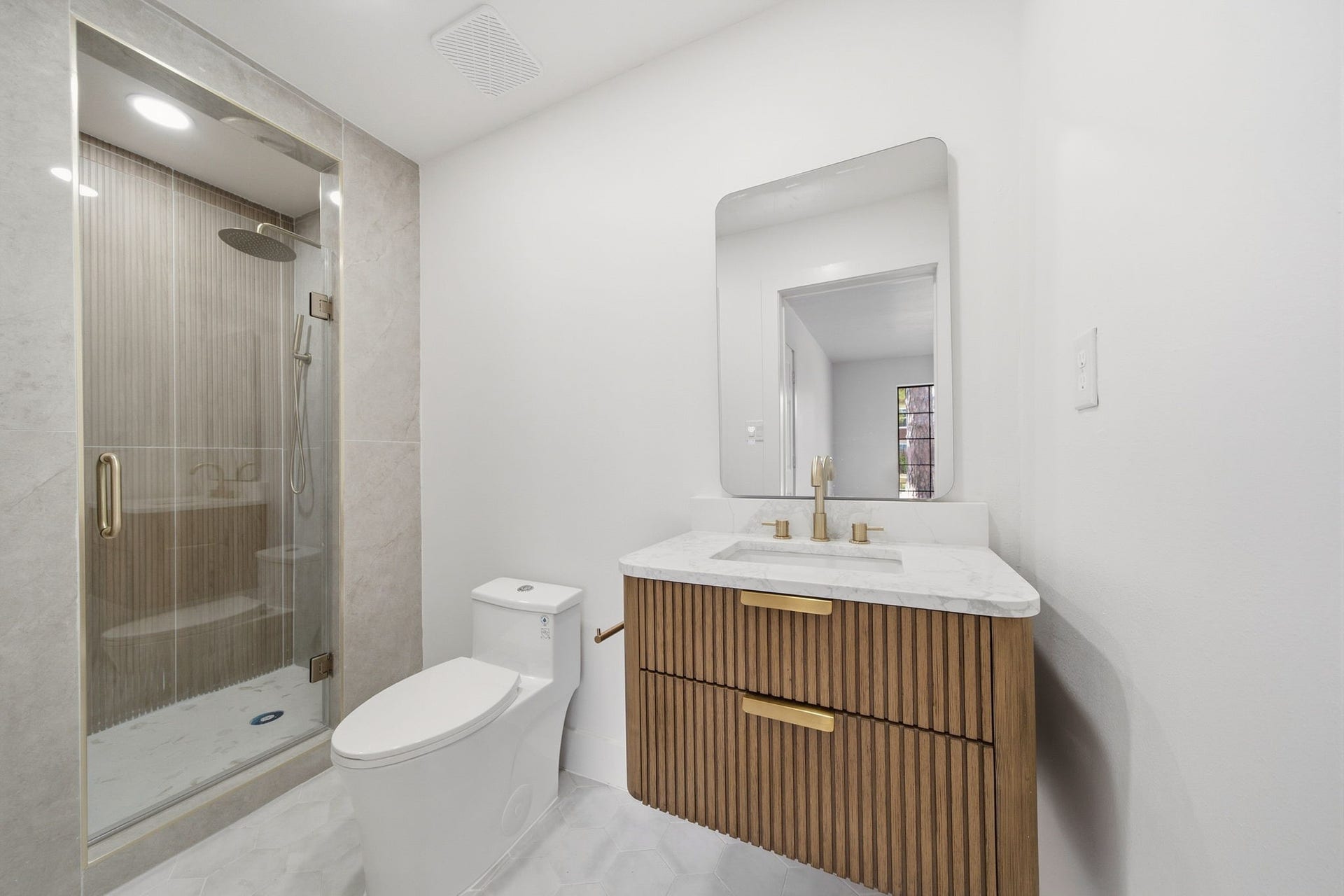 2304 Eagles Way, Pearland, TX 77581 Stylish full bath pairs a sculptural fluted vanity with warm brass finishes and a sleek glass-enclosed shower.