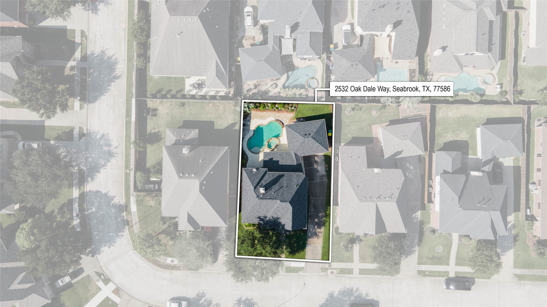 2532 Oak Dale Way, Seabrook, TX 77586 This aerial view showcases the full property, including an extended driveway leading to a detached garage with plenty of room for parking. The backyard pool and spa sit tucked behind the home, with mature trees and lush landscaping adding privacy and curb appeal.