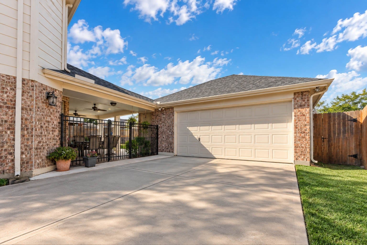 2532 Oak Dale Way, Seabrook, TX 77586 A two car garage with a paneled door sits at the back of the property, with a wide concrete driveway offering generous room for parking and turning around. A wrought iron gate secures the covered patio, and a wood gate beside the garage leads into the backyard.