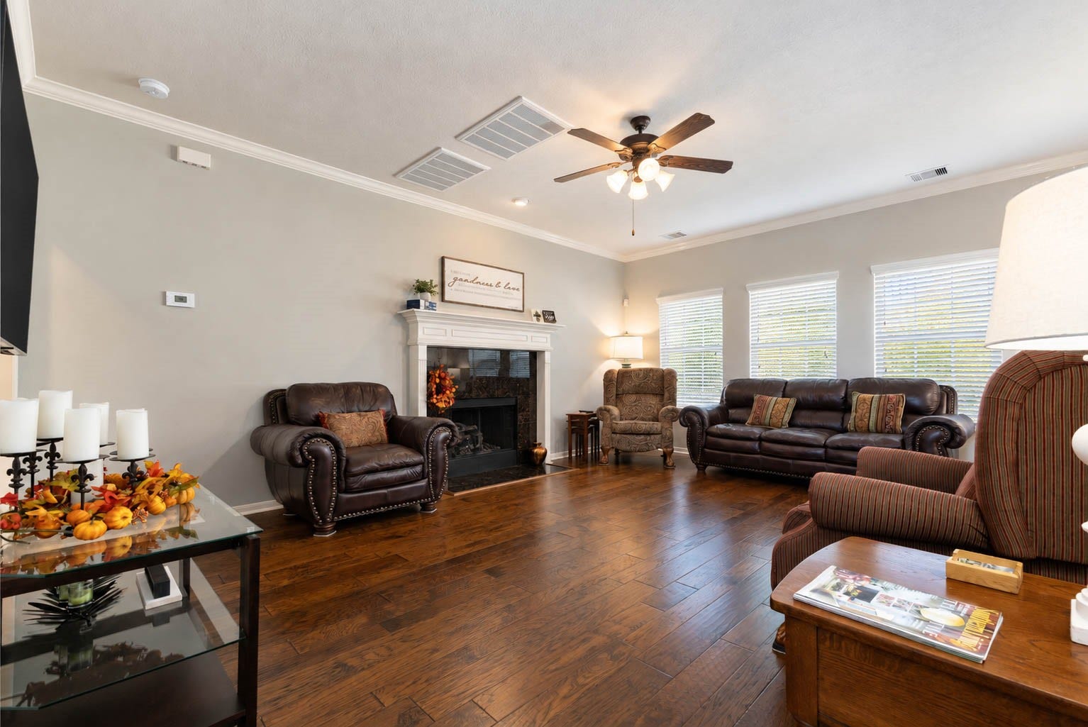 2532 Oak Dale Way, Seabrook, TX 77586 This generously sized living room welcomes you with stunning hardwood floors, soft neutral paint, and crown molding for a polished finish. Three large windows frame views of the backyard and fill the space with natural light, while a cozy fireplace with a classic white mantel takes center stage.