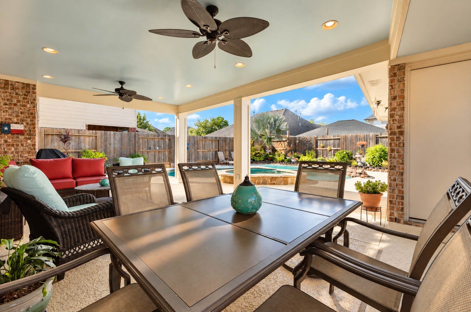 2532 Oak Dale Way, Seabrook, TX 77586 Head outside to a generously sized covered patio, where two ceiling fans and recessed lighting keep the space comfortable from morning coffee to evening gatherings. There is room for both a dining table and a separate seating area, with views of the pool and spa just beyond the columns.
