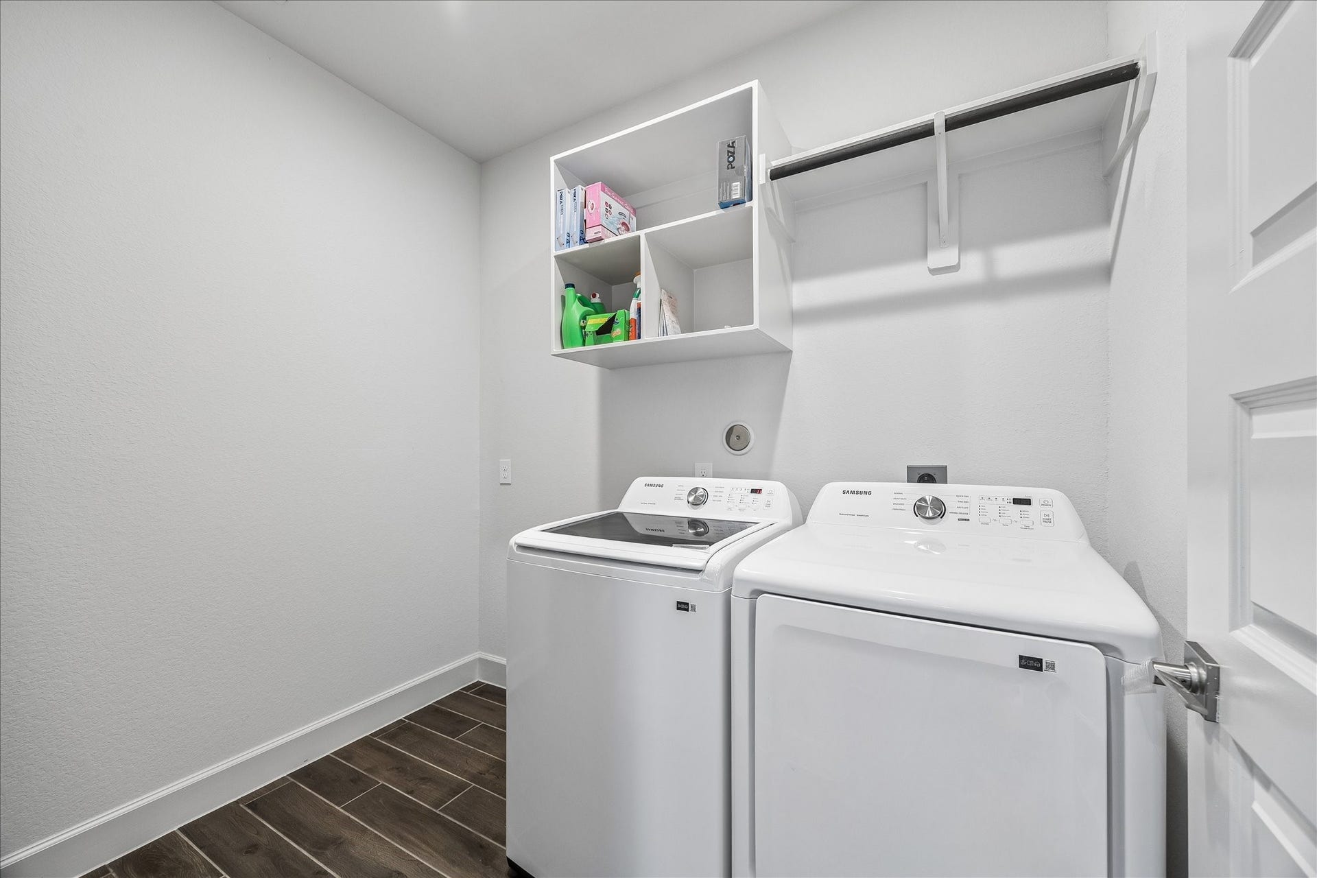 Dedicated utility room with upper shelving, hanging rod, and extra space for storage or organization