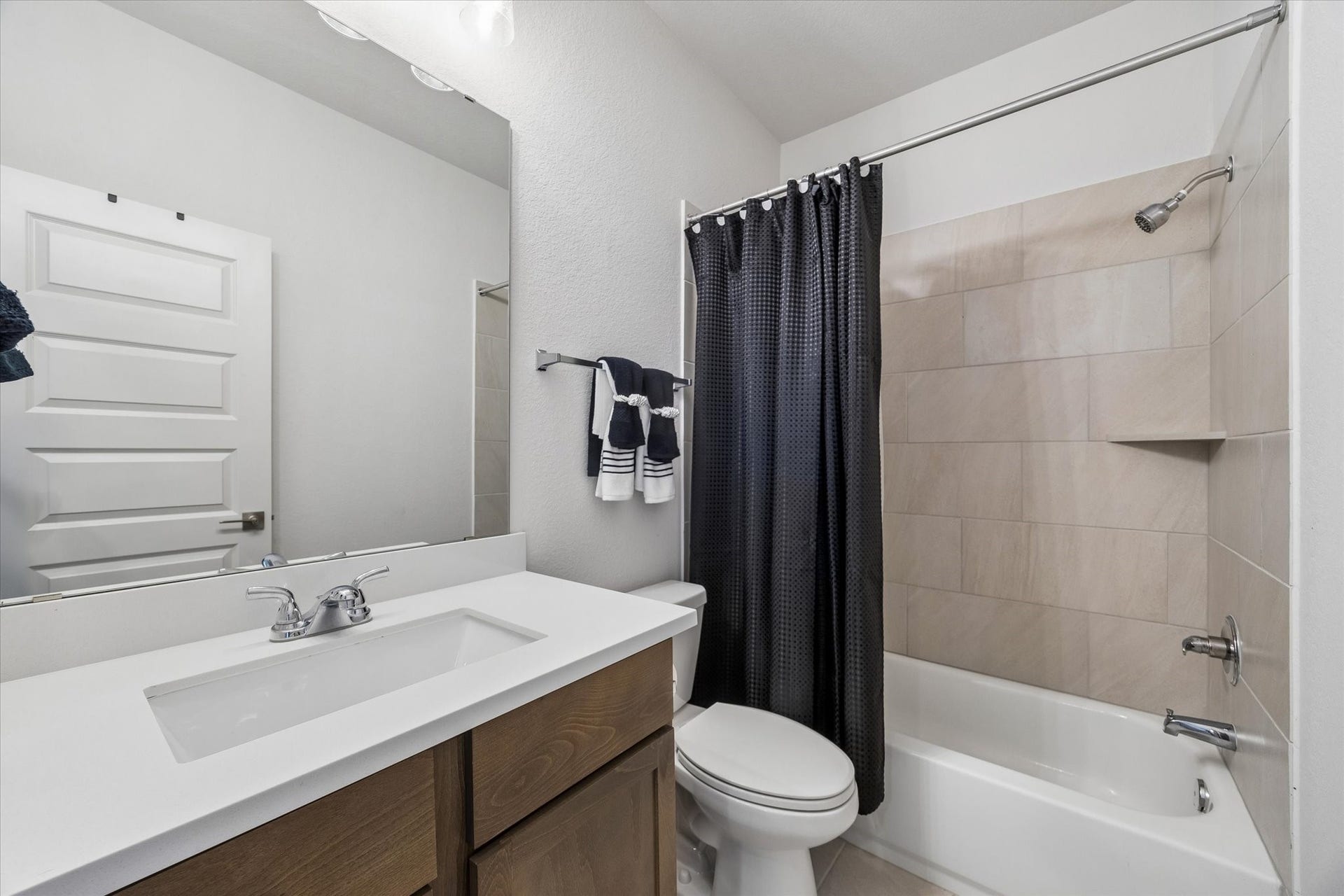 Full upstairs bathroom with a quartz vanity, tiled tub/shower, and modern finishes