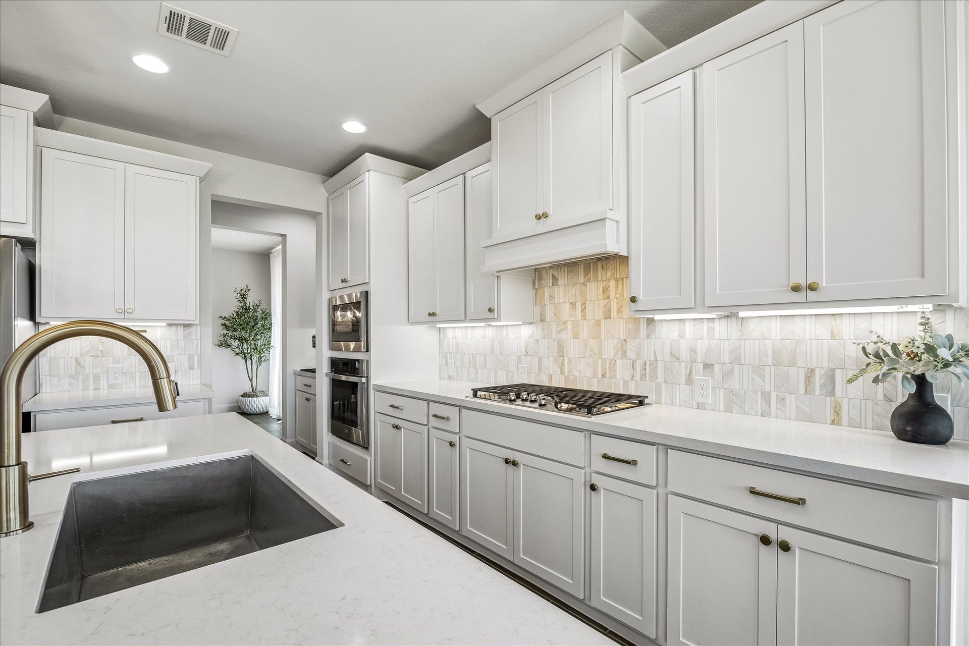 Gourmet kitchen features custom cabinetry, quartz countertops, under-cabinet lighting and a designer tile backsplash