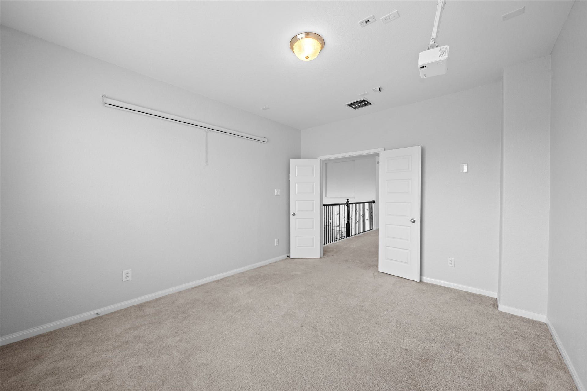 17315 Tomintoul Path, Richmond, TX 77407 Another view of the spacious media room, highlighting the ceiling-mounted projector, retractable screen, and ample space for a customized home theater setup.