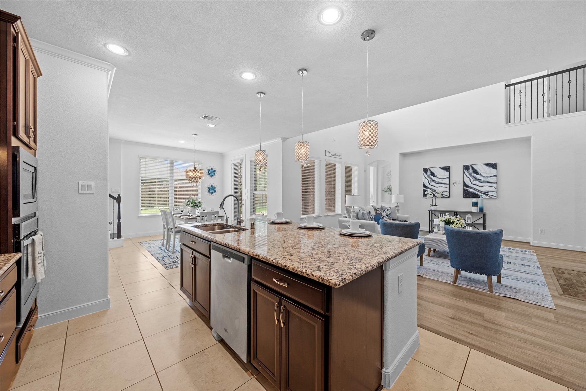 17315 Tomintoul Path, Richmond, TX 77407 A sweeping perspective captures the grand granite island, sunlit breakfast nook, and seamless connection to the family room, embodying sophisticated open-concept family.