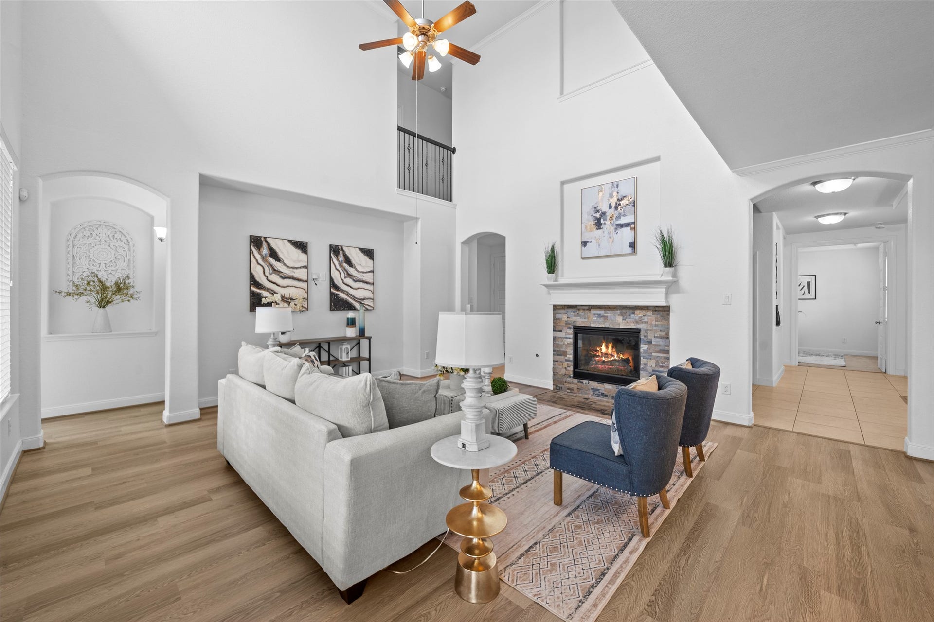 17315 Tomintoul Path, Richmond, TX 77407 Grand proportions define this sophisticated family room, where dramatic ceiling height, an upper-level overlook, and a striking fireplace establish an atmosphere of timeless refinement.