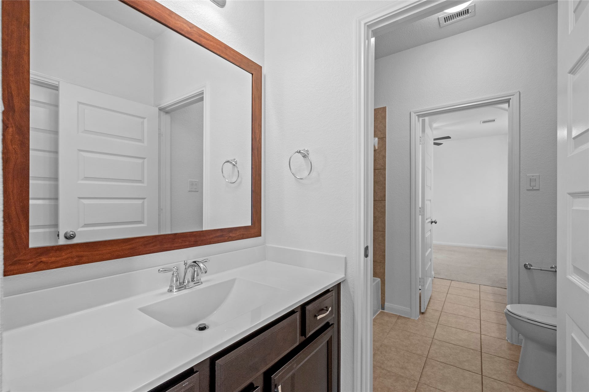 17315 Tomintoul Path, Richmond, TX 77407 Convenient adjoining bathroom featuring a spacious vanity, large framed mirror, and easy access from the secondary bedroom.