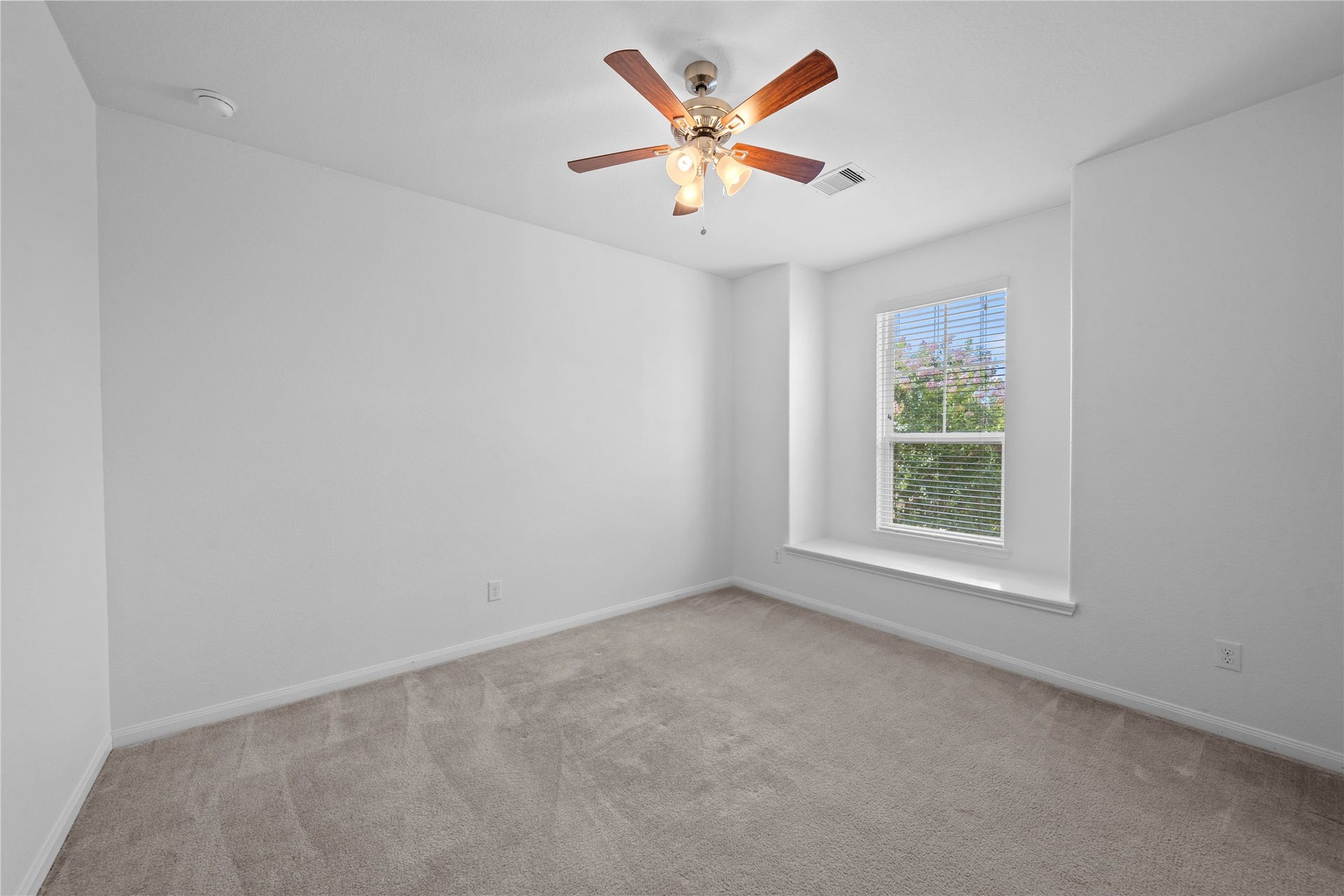 17315 Tomintoul Path, Richmond, TX 77407 Spacious third bedroom featuring plush carpeting, a ceiling fan, and a large window with a built-in ledge for added natural light and character.