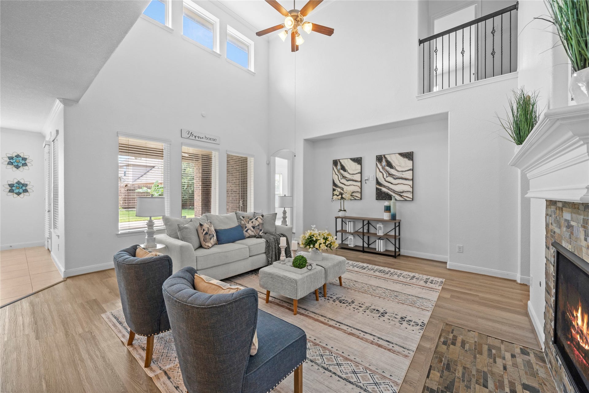 17315 Tomintoul Path, Richmond, TX 77407 A breathtaking two-story family room captivates with soaring ceilings, clerestory windows, a stone-accented fireplace, and expansive natural light creating an impressive sense of grandeur.