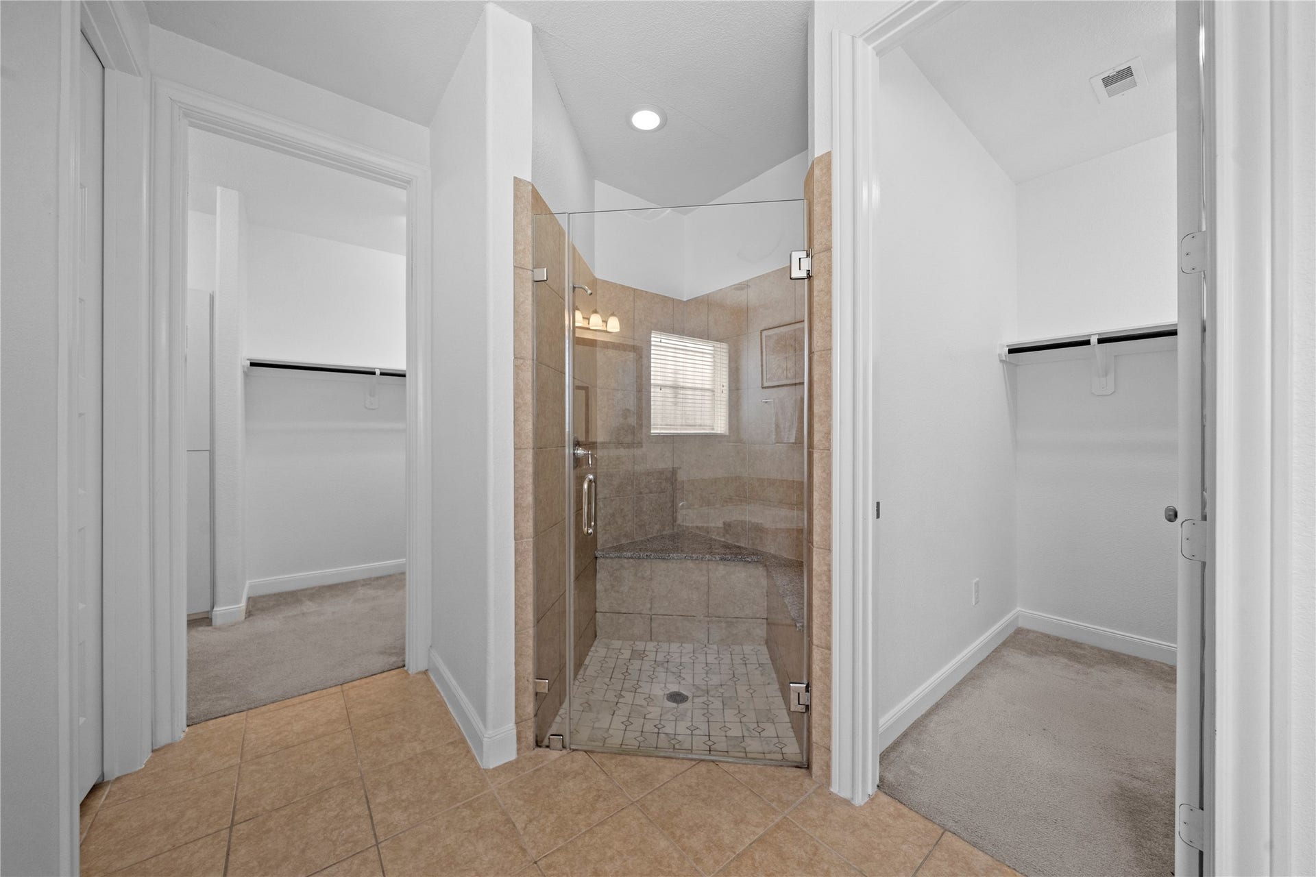 17315 Tomintoul Path, Richmond, TX 77407 A glass-enclosed walk-in shower with tiled surround and built-in bench is complemented by dual walk-in closets, offering privacy, comfort, and exceptional storage.