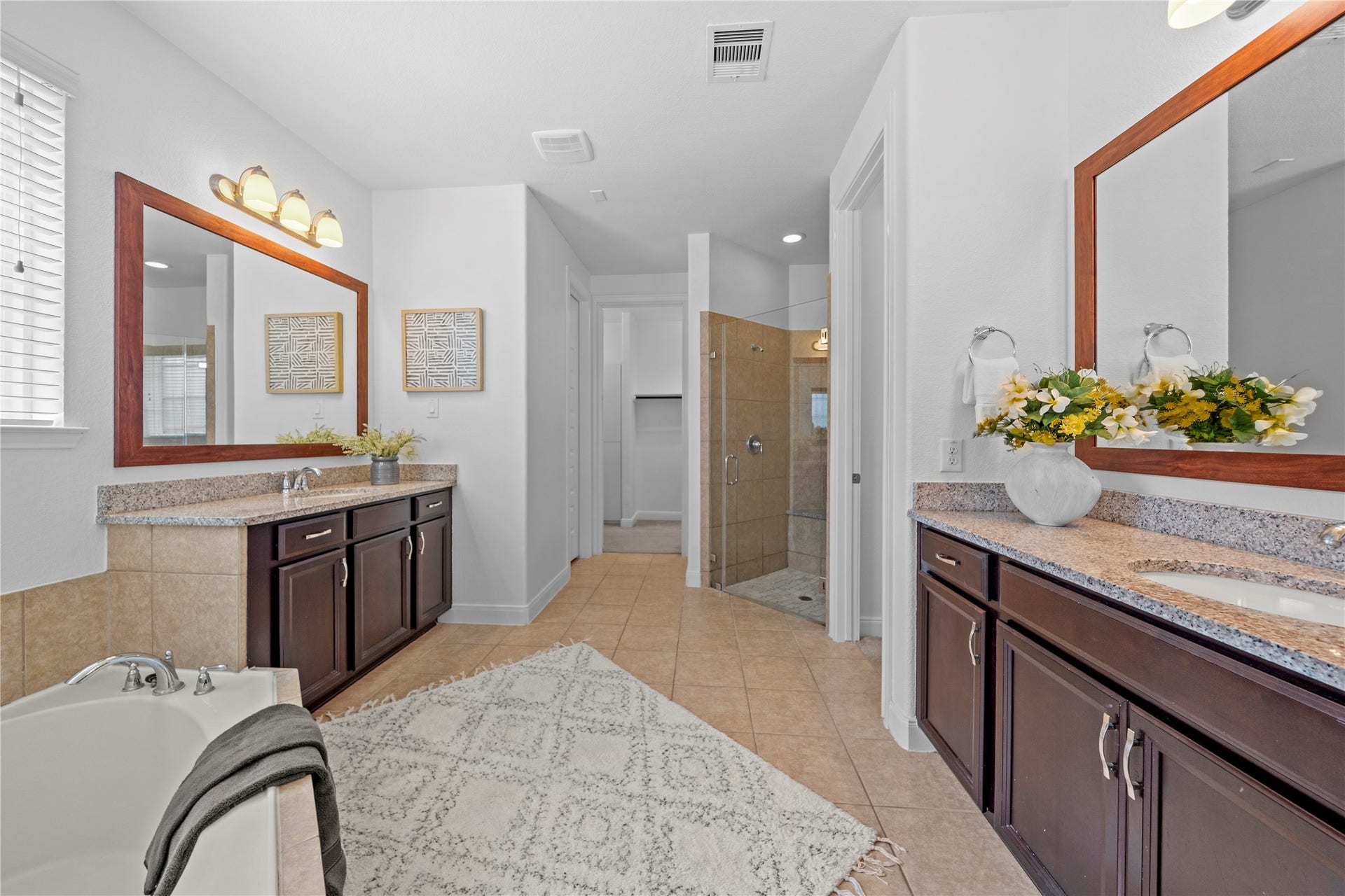 17315 Tomintoul Path, Richmond, TX 77407 A luxurious primary bath features separate granite-topped vanities, a soaking tub, glass-enclosed shower, and spacious layout crafted for comfort and relaxation.