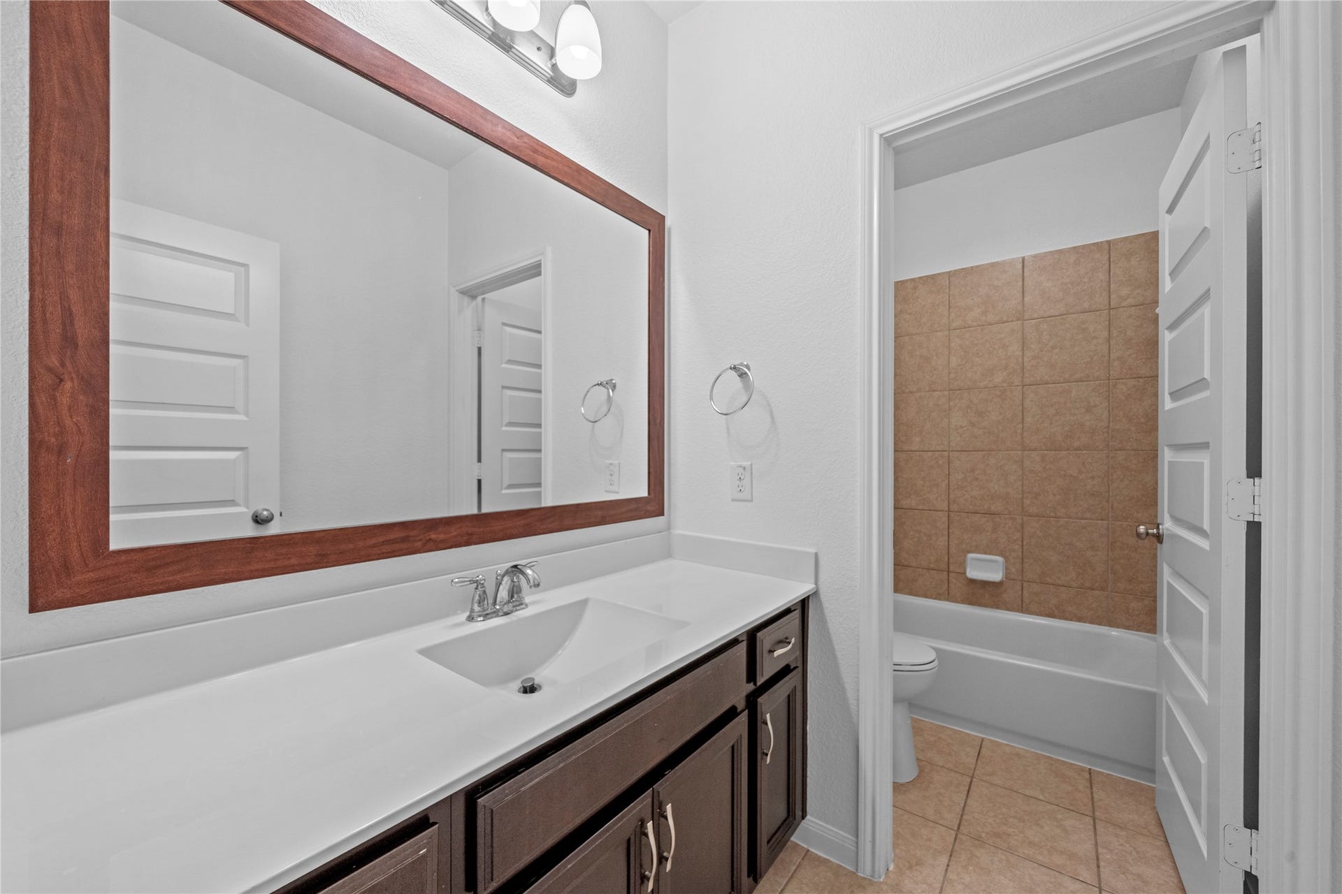 17315 Tomintoul Path, Richmond, TX 77407 Bathroom, showcasing the spacious vanity, large framed mirror, and tub/shower combination with tiled surround.