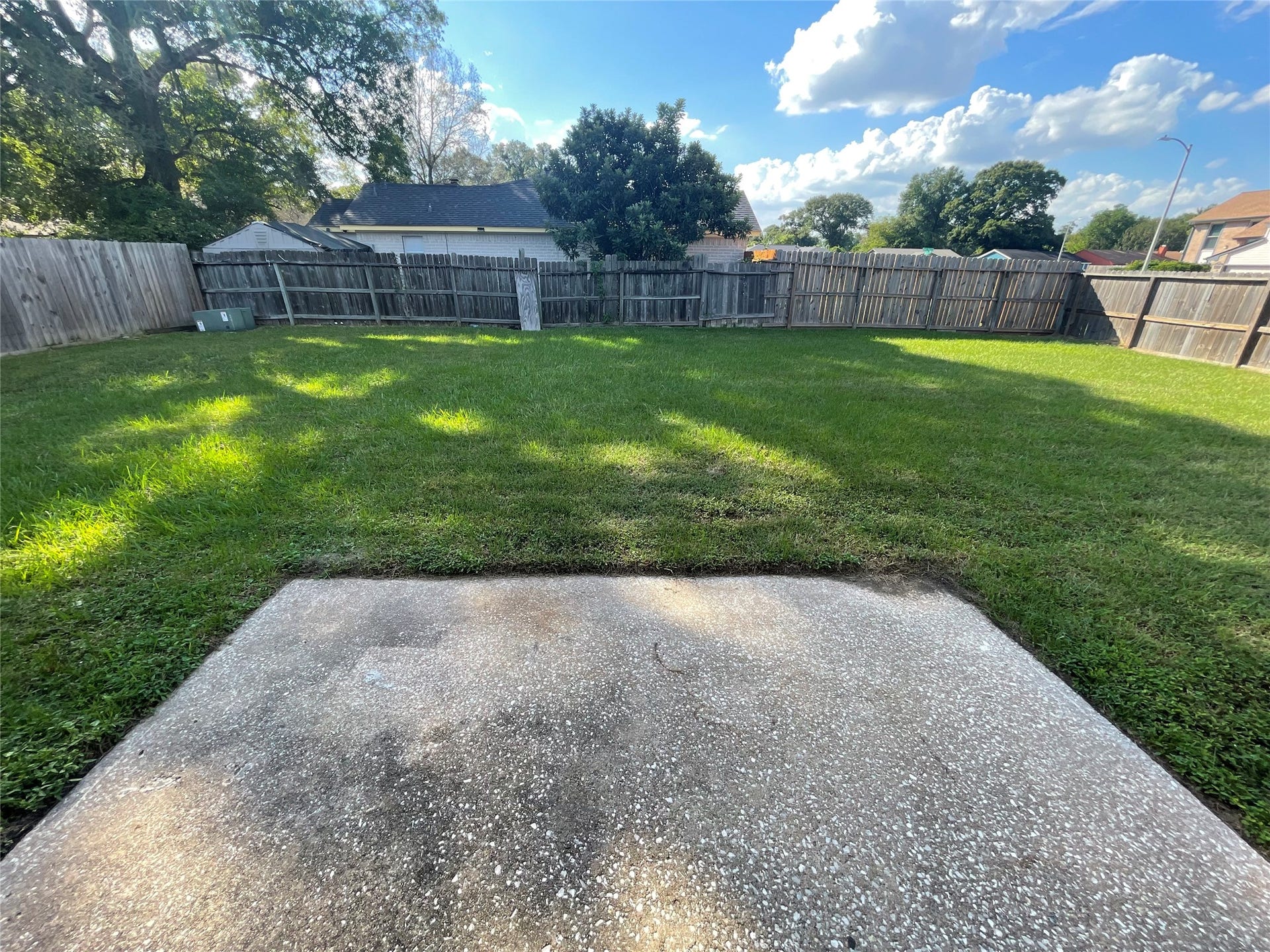 Enjoy the spacious backyard featuring a large grassy lawn, mature trees, and a concrete patio area. The open outdoor space offers plenty of possibilities for entertaining, gardening, outdoor activities, or simply relaxing and enjoying the fresh air.