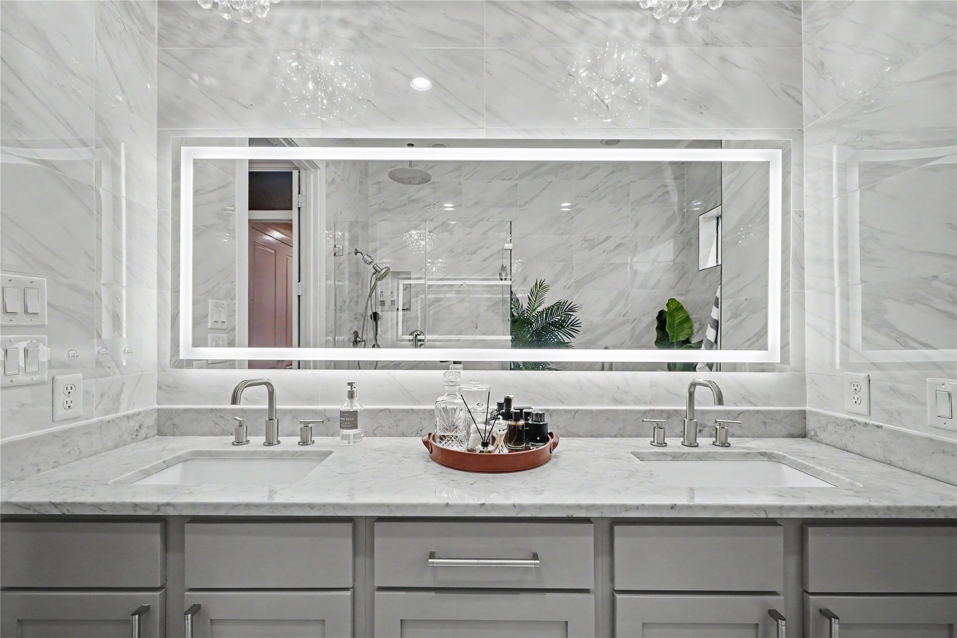 Incredible lighted-mirror and dual vanities in this primary bathroom.