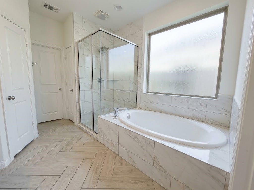 8822 SPINNING MILL DRIVE, Missouri City, TX 77459 A SEPARATE SOAKING TUB SITS BENEATH A LARGE WINDOW, NEXT TO THE GLASS-ENCLOSED SHOWER.