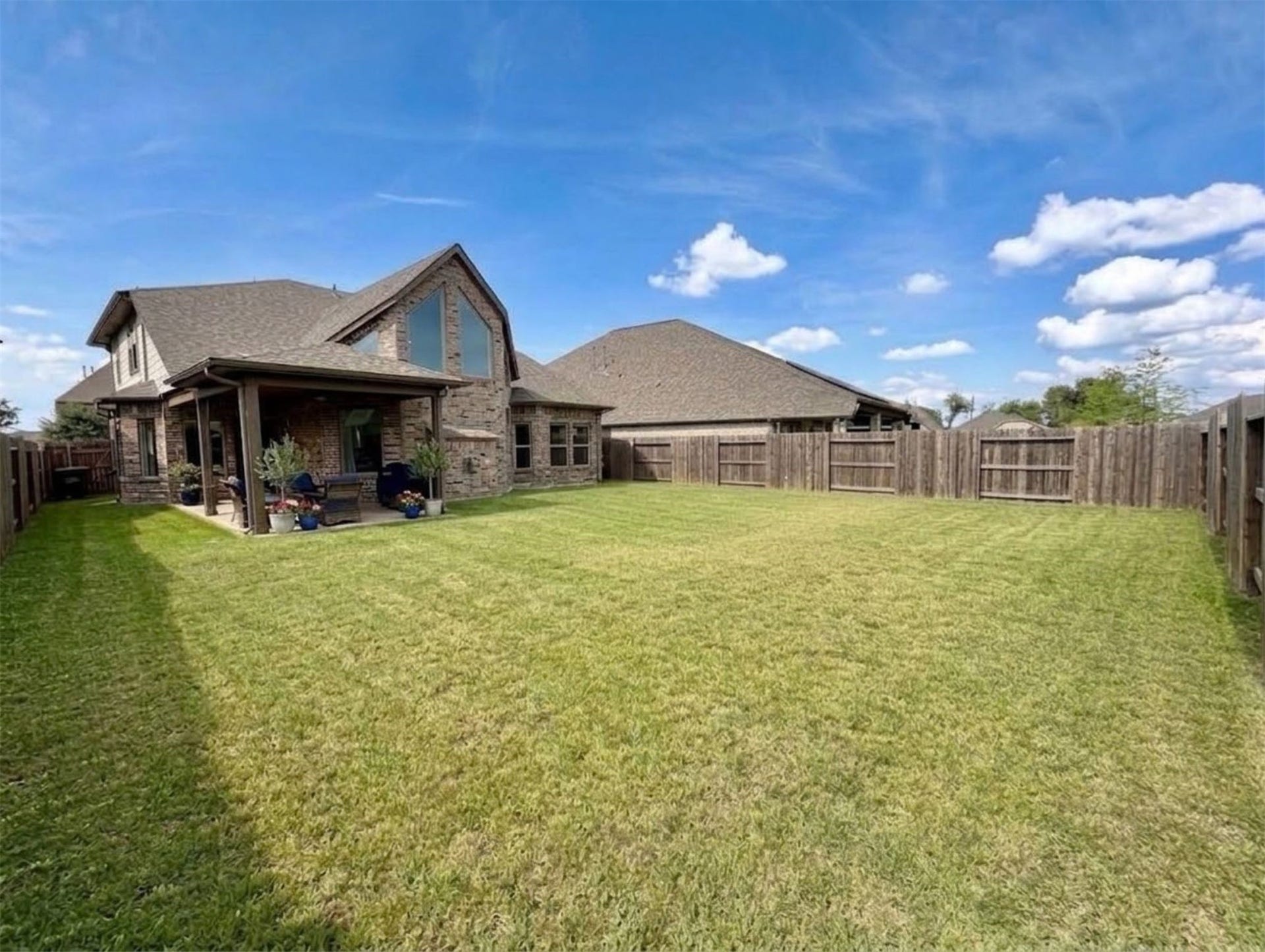 8822 SPINNING MILL DRIVE, Missouri City, TX 77459 THE FENCED BACKYARD OFFERS A WIDE STRETCH OF LAWN, WITH THE COVERED PATIO JUST OFF THE HOME.