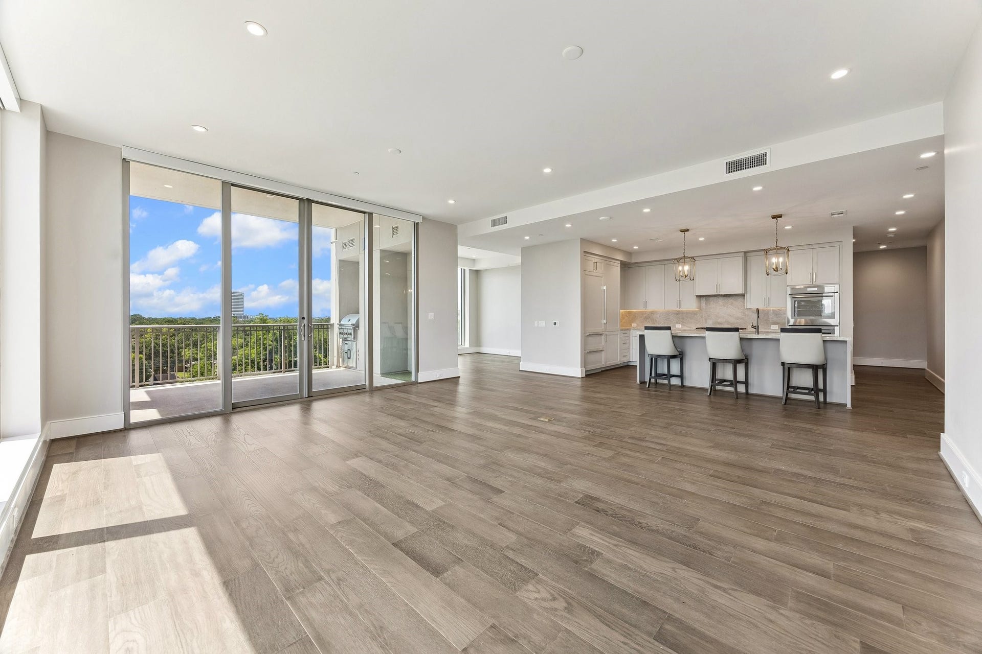 5656 San Felipe Street, Unit 701, Houston, TX 77056 Actual unit photo showcasing the seamless Living /Kitchen flow with double sliding glass doors leading to a large private terrace.