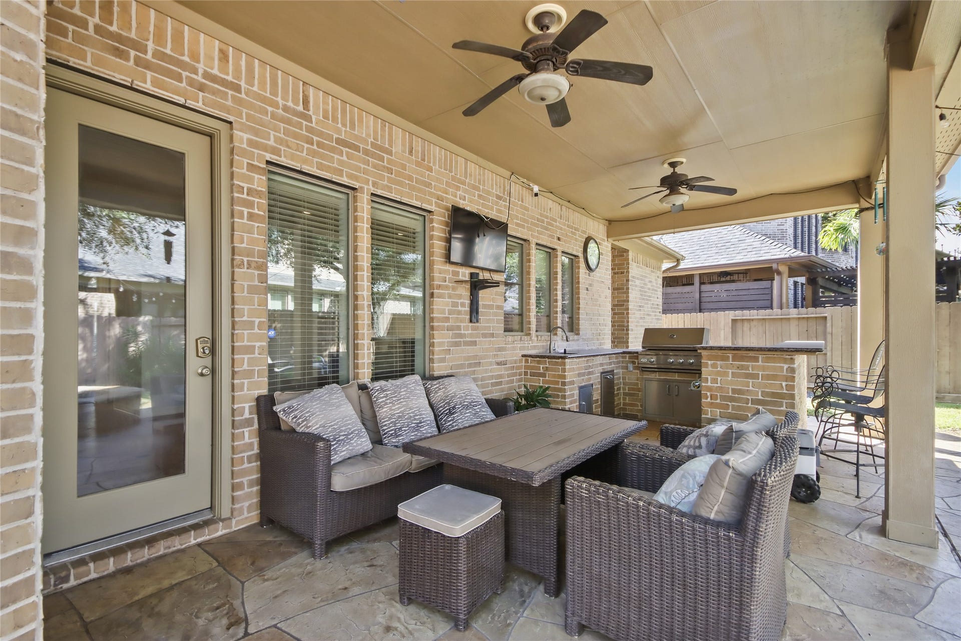 27906 Iberville Glen Dr, Katy, TX 77494 Enjoy outdoor living at its finest with this spacious covered patio, featuring ceiling fans, a comfortable seating area, and an outdoor kitchen.