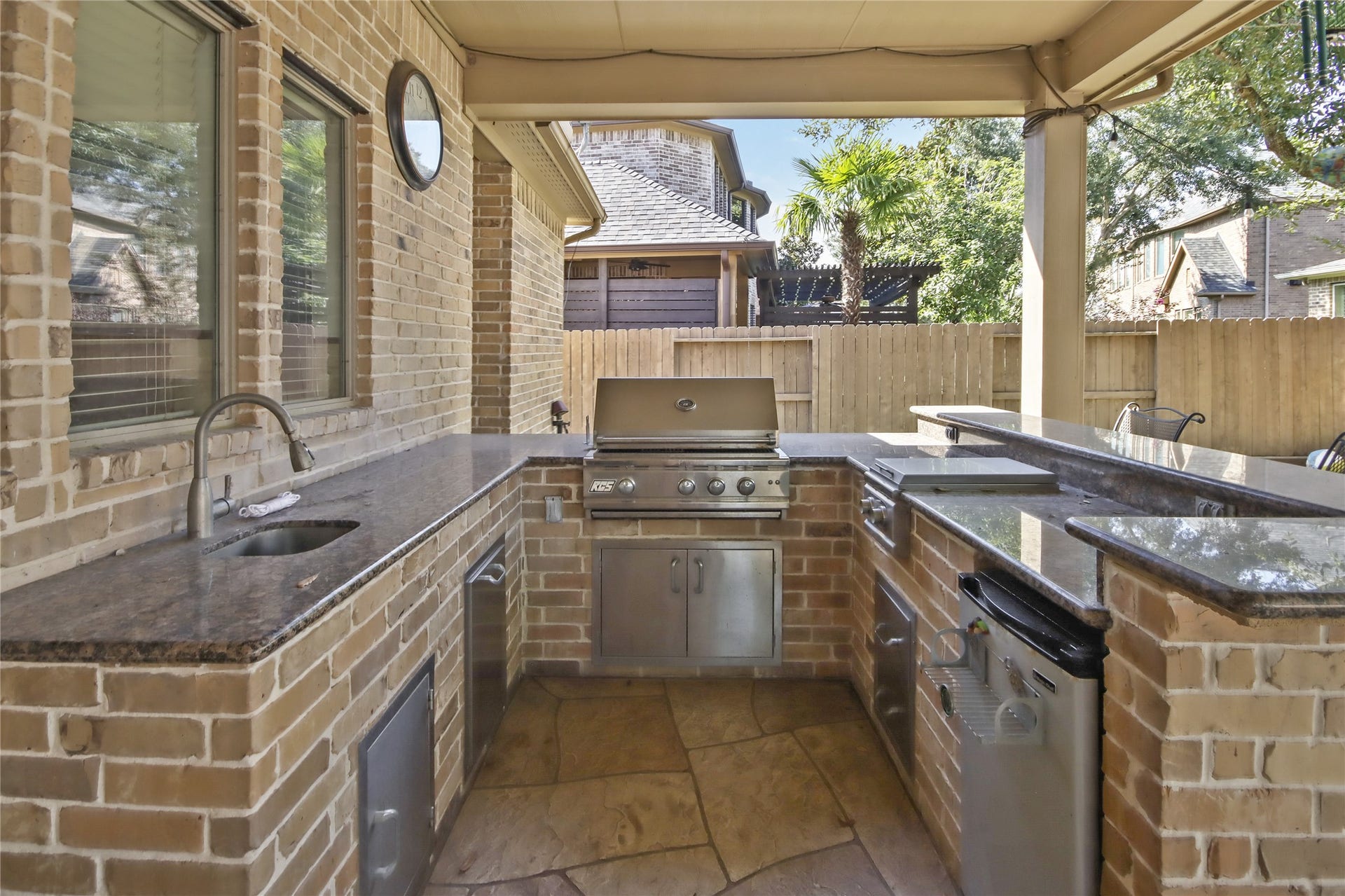 27906 Iberville Glen Dr, Katy, TX 77494 A fully covered outdoor kitchen is equipped with a built-in grill, side burner, and refrigerator, sink. Stone countertop, making outdoor entertainment effortless.