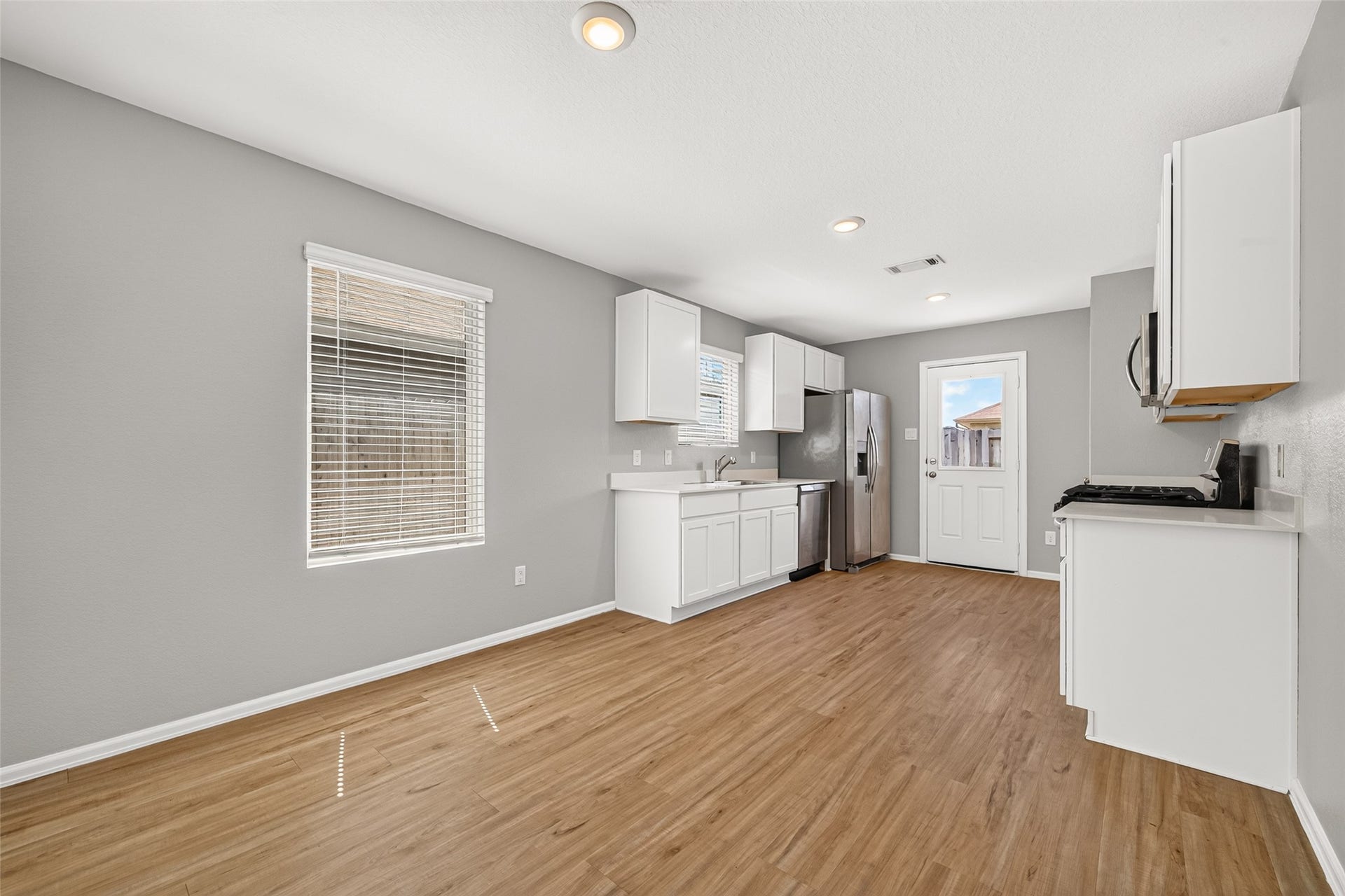 19494 Rosali Meadow Drive, New Caney, TX 77357 Modern kitchen with sleek stainless steel appliances, white cabinetry, and warm wood flooring, offering a bright and airy atmosphere.
