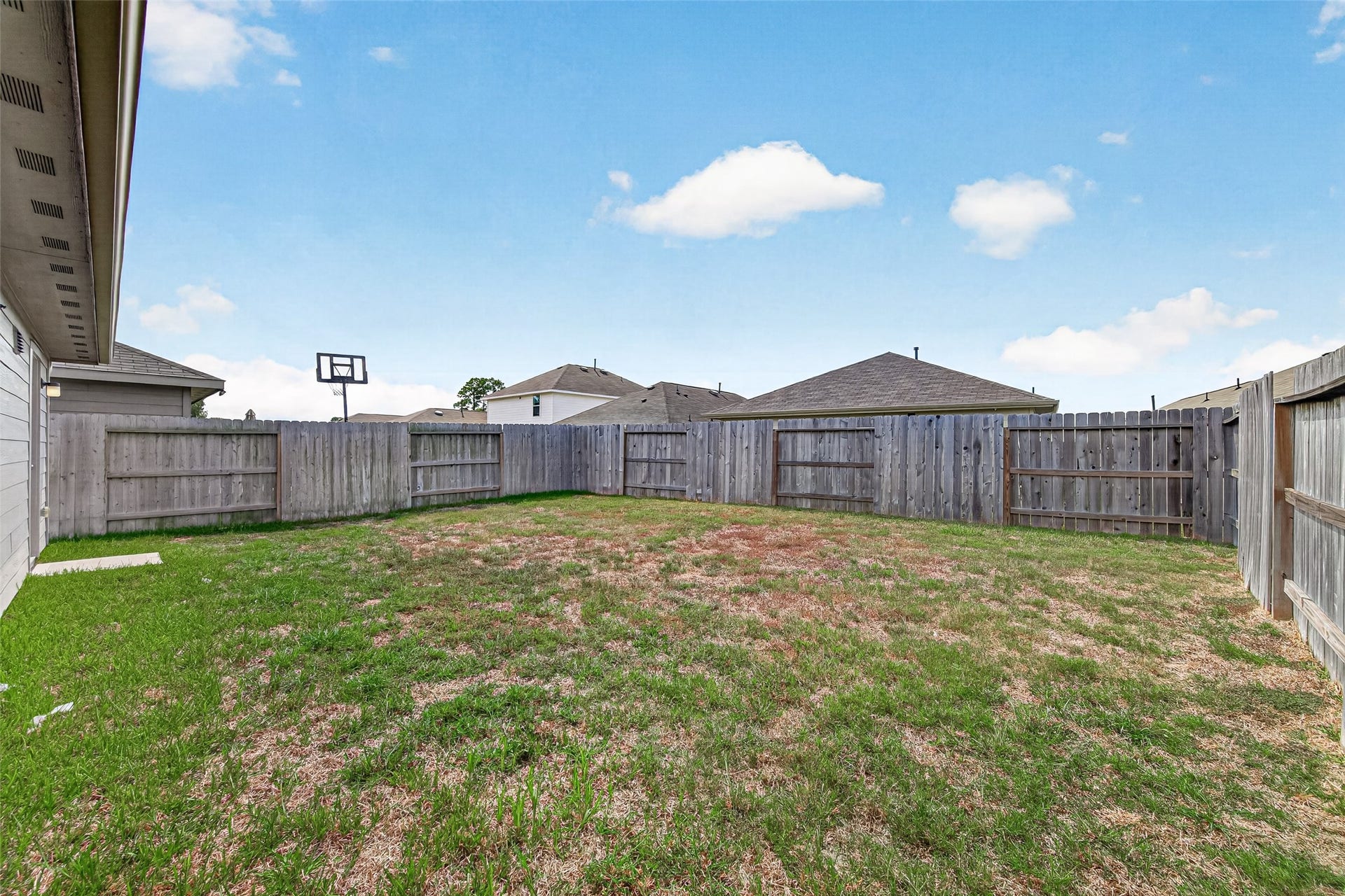 19494 Rosali Meadow Drive, New Caney, TX 77357 Spacious fenced backyard perfect for outdoor activities and family gatherings, complete with a basketball hoop for added fun.