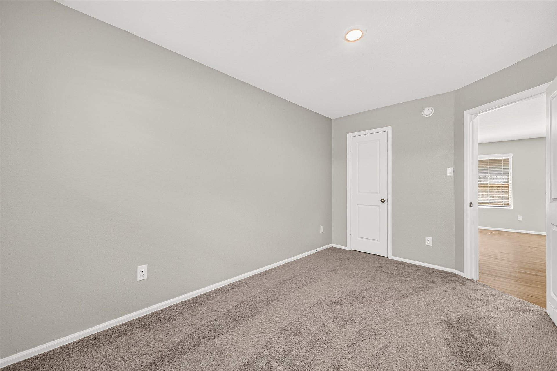 19494 Rosali Meadow Drive, New Caney, TX 77357 Cozy room with soft carpeting, neutral gray walls, and a recessed light, offering a serene space with convenient access to an adjacent room.