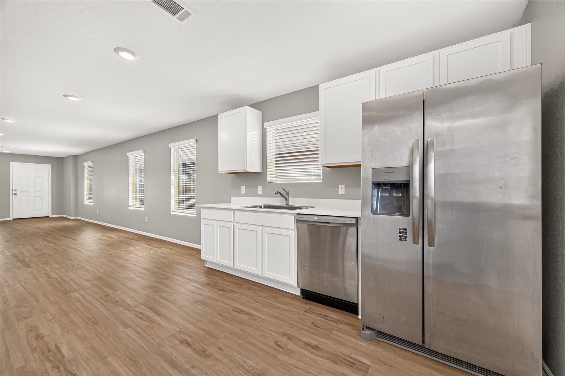 19494 Rosali Meadow Drive, New Caney, TX 77357 Spacious kitchen with sleek stainless steel appliances, ample white cabinetry, and beautiful wood flooring, seamlessly flowing into the open living area.