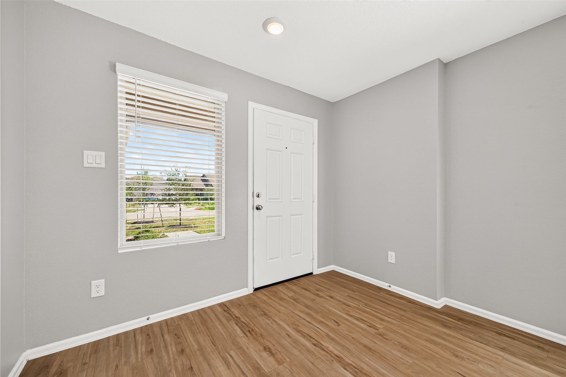 19494 Rosali Meadow Drive, New Caney, TX 77357 Inviting entryway with sleek hardwood floors, neutral gray walls, and abundant natural light through a large window, creating a bright and welcoming atmosphere.