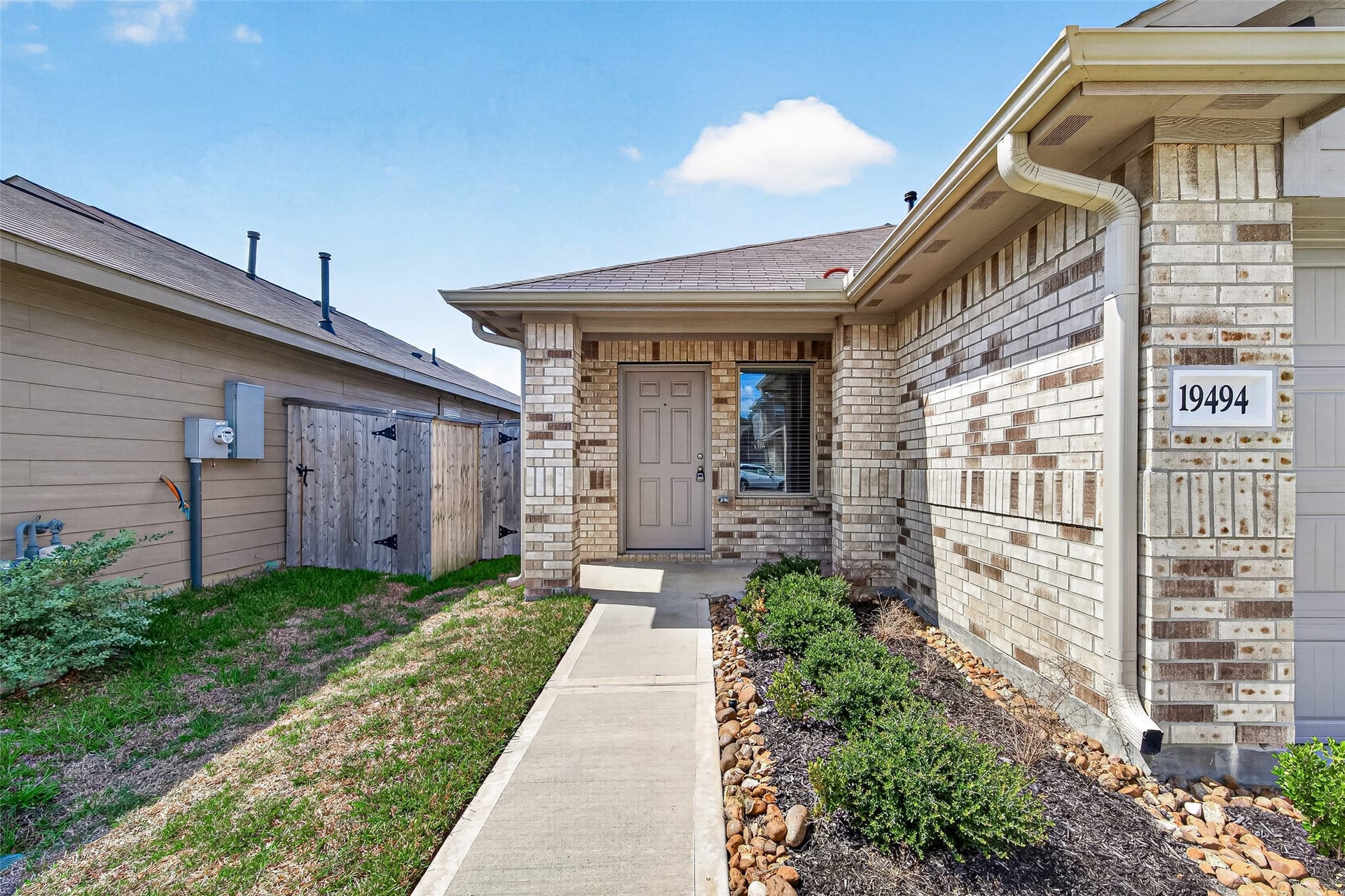 19494 Rosali Meadow Drive, New Caney, TX 77357 Inviting entrance with a welcoming pathway, surrounded by well-maintained landscaping and a stylish brick exterior.